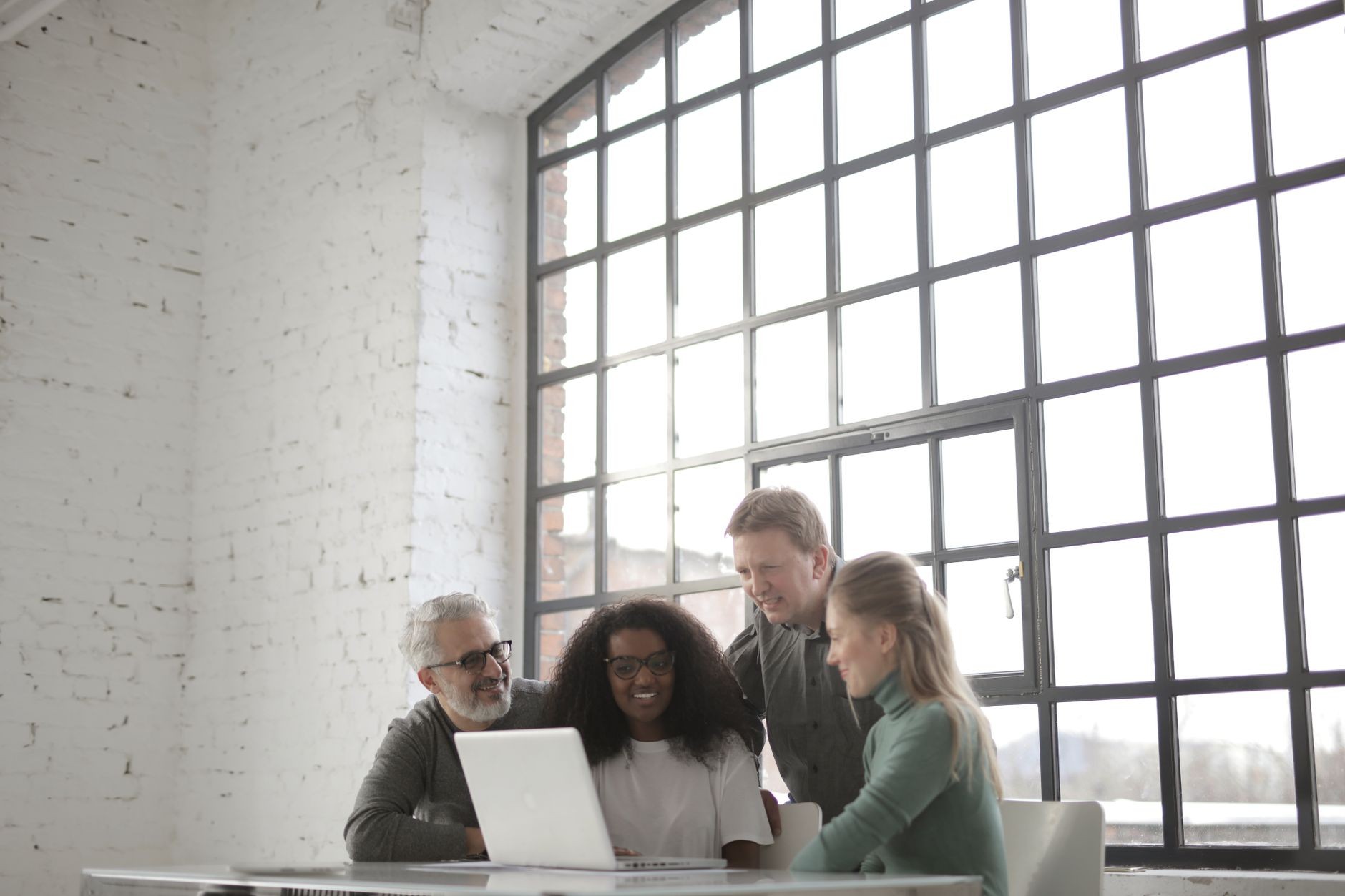 Small team reviewing deals together around a laptop in a bright office