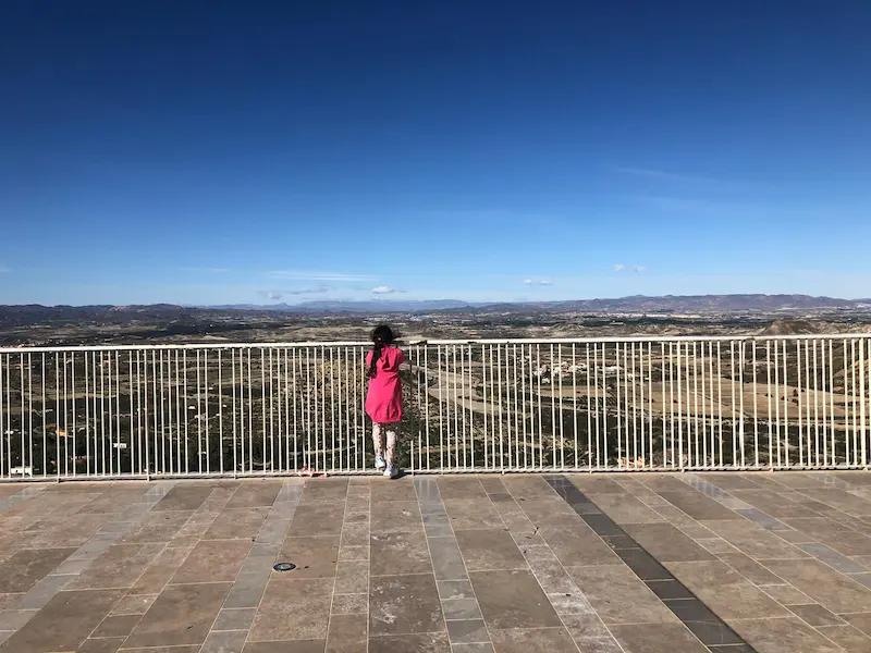 Viewing Point at Mojacar Pueblo - showing a girl in pinking looking over the railings at the landscape beyond.
