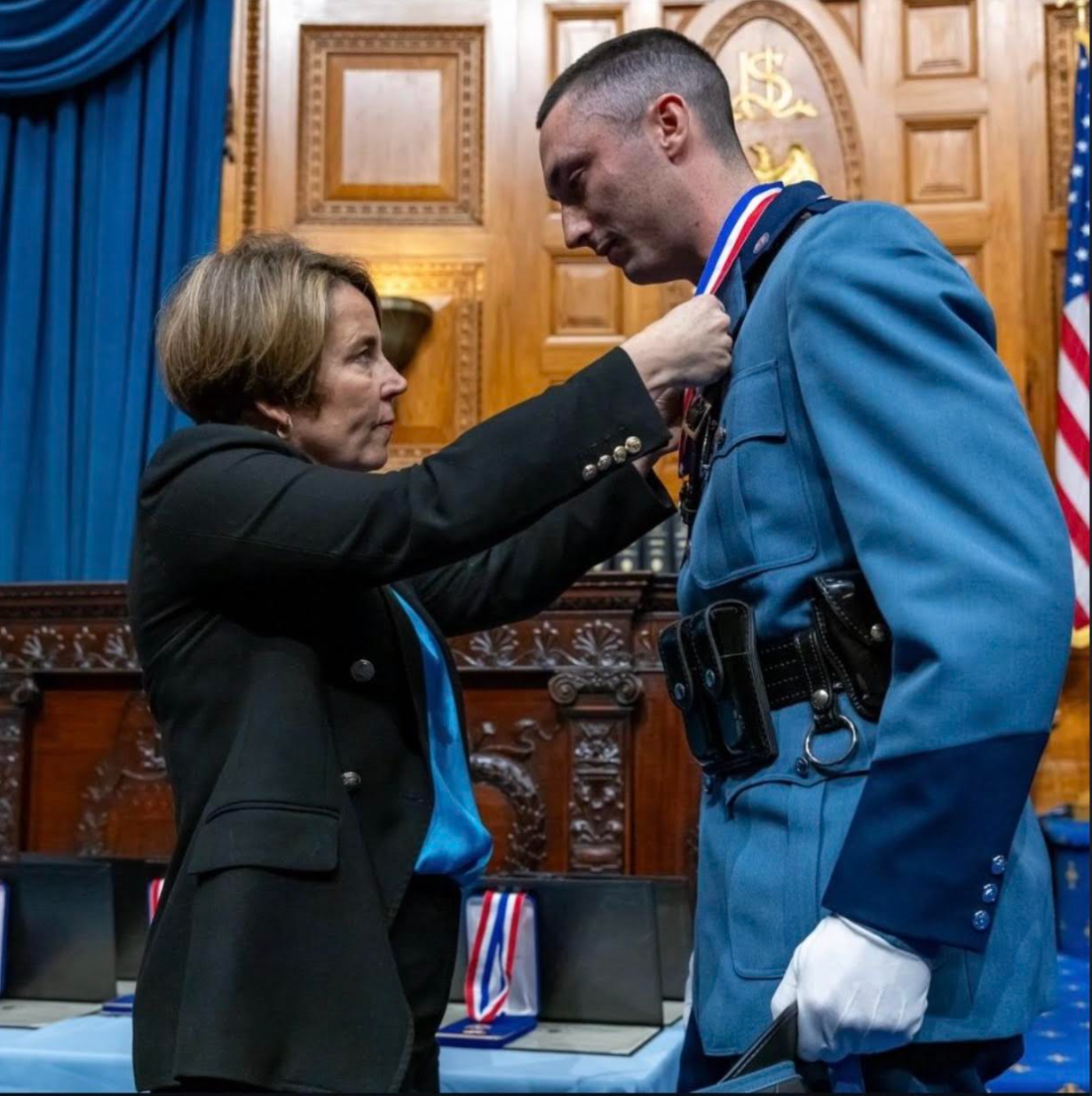 Maura Healey pinning a medal on trooper costello at state house.