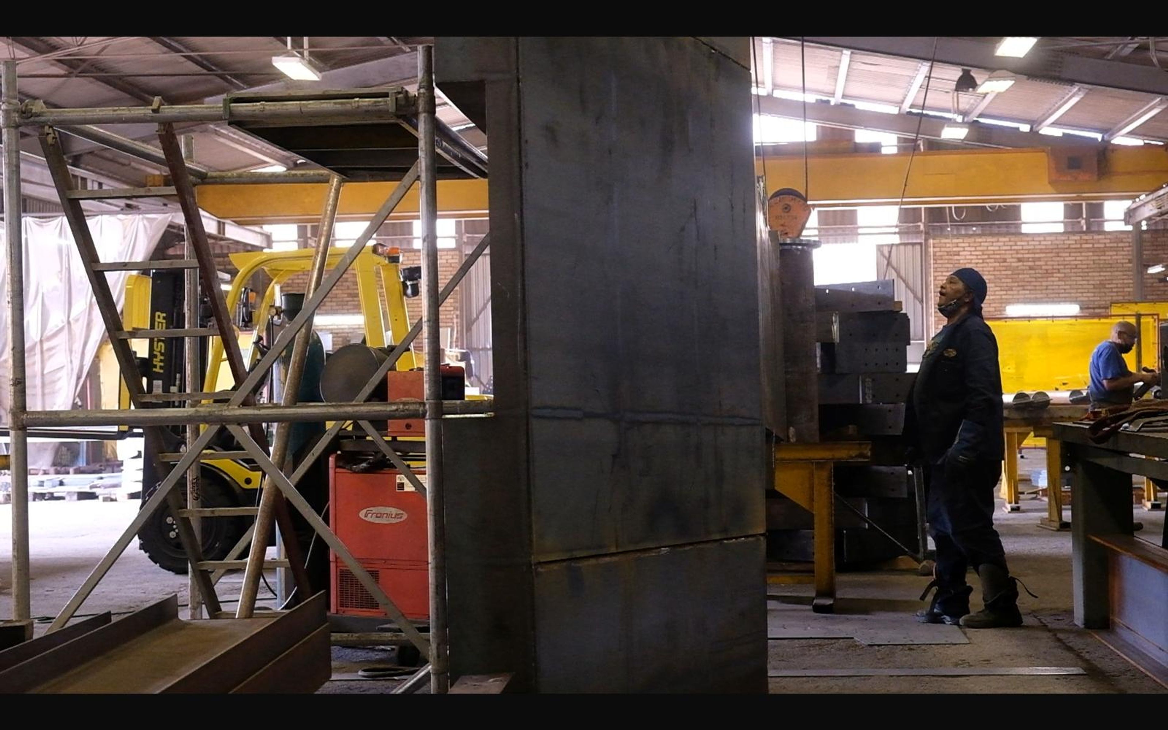 Workers beside a large steel section in the bay