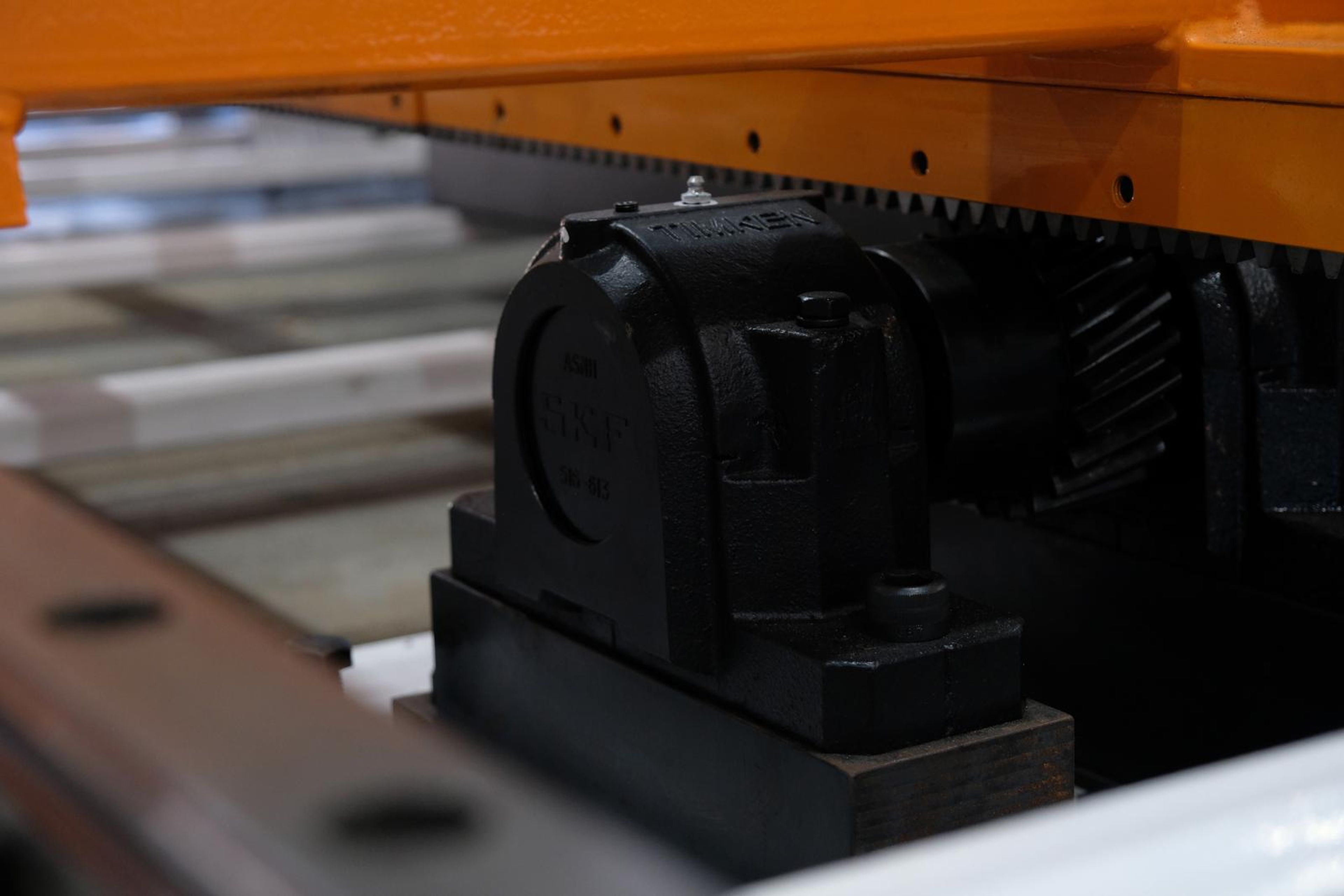 Black bearing housing beneath an orange beam on a rack