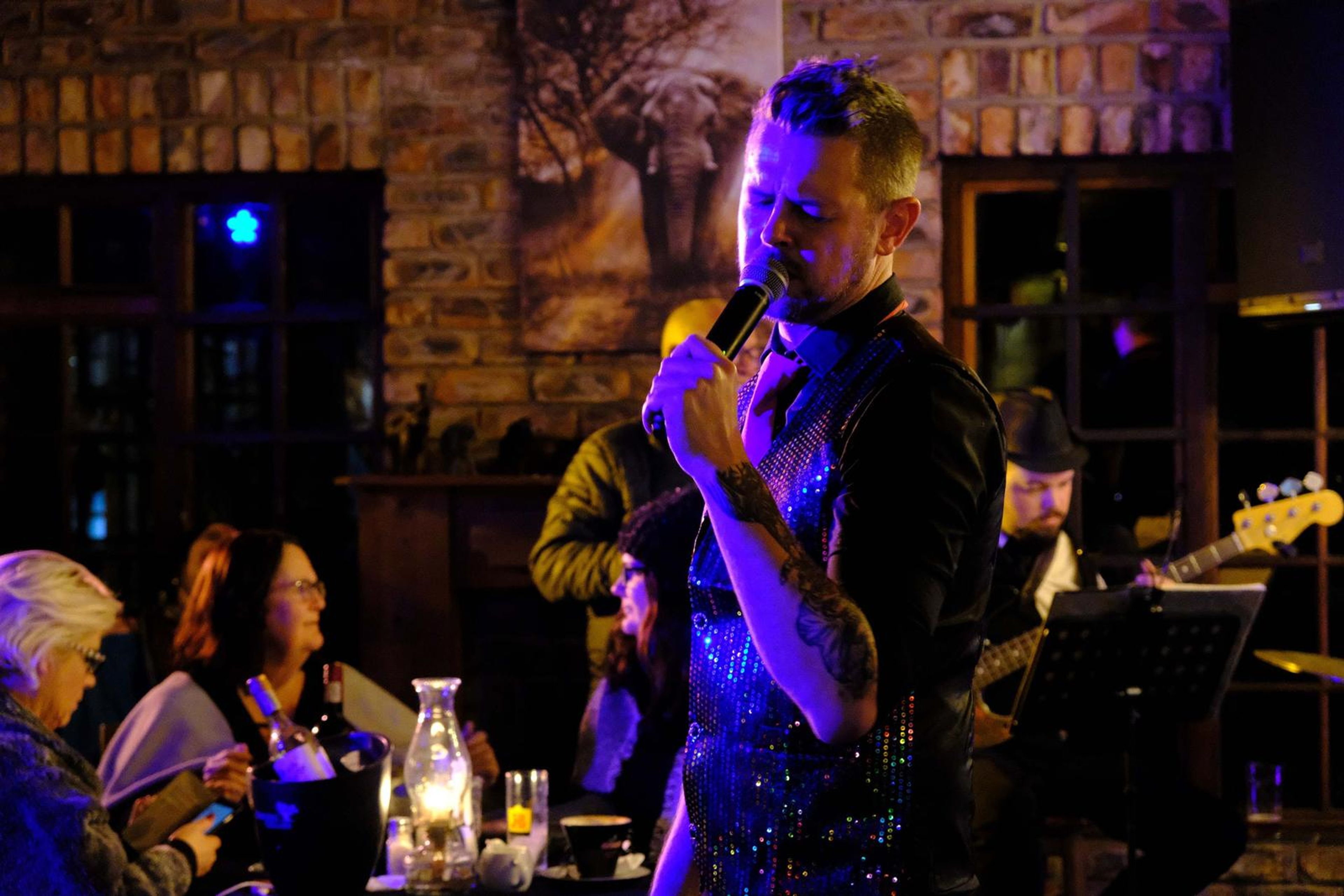 Lead singer singing into the microphone beside a candle-lit table