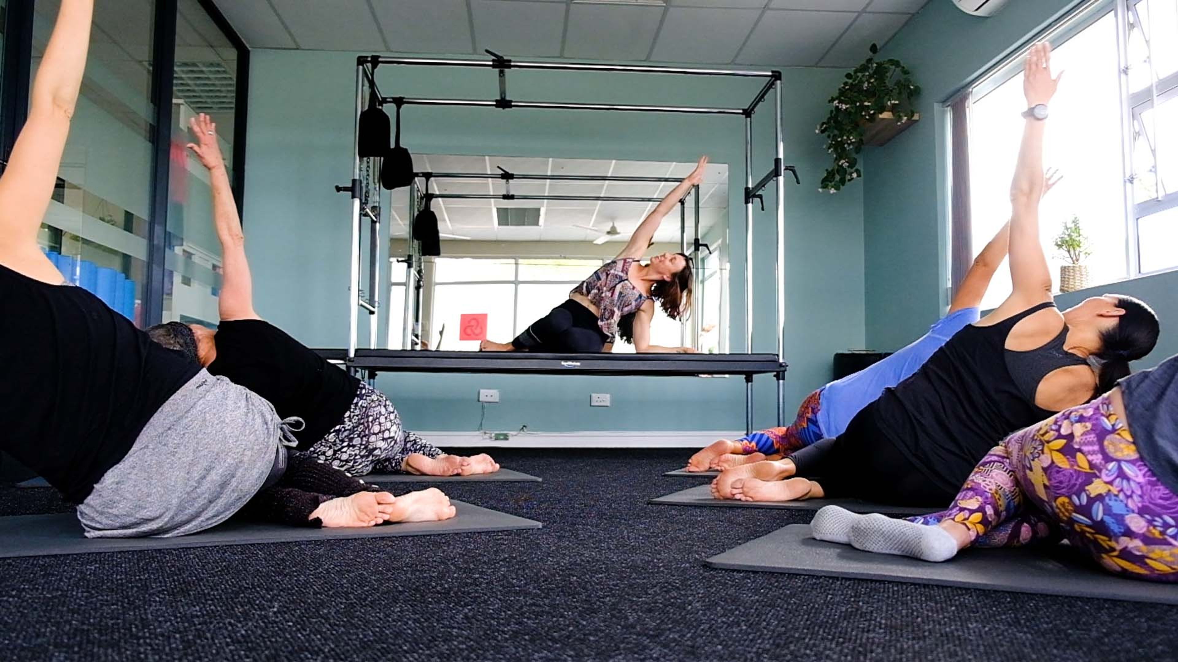 Wide view of a Pilates class working through side-lying stretches on mats