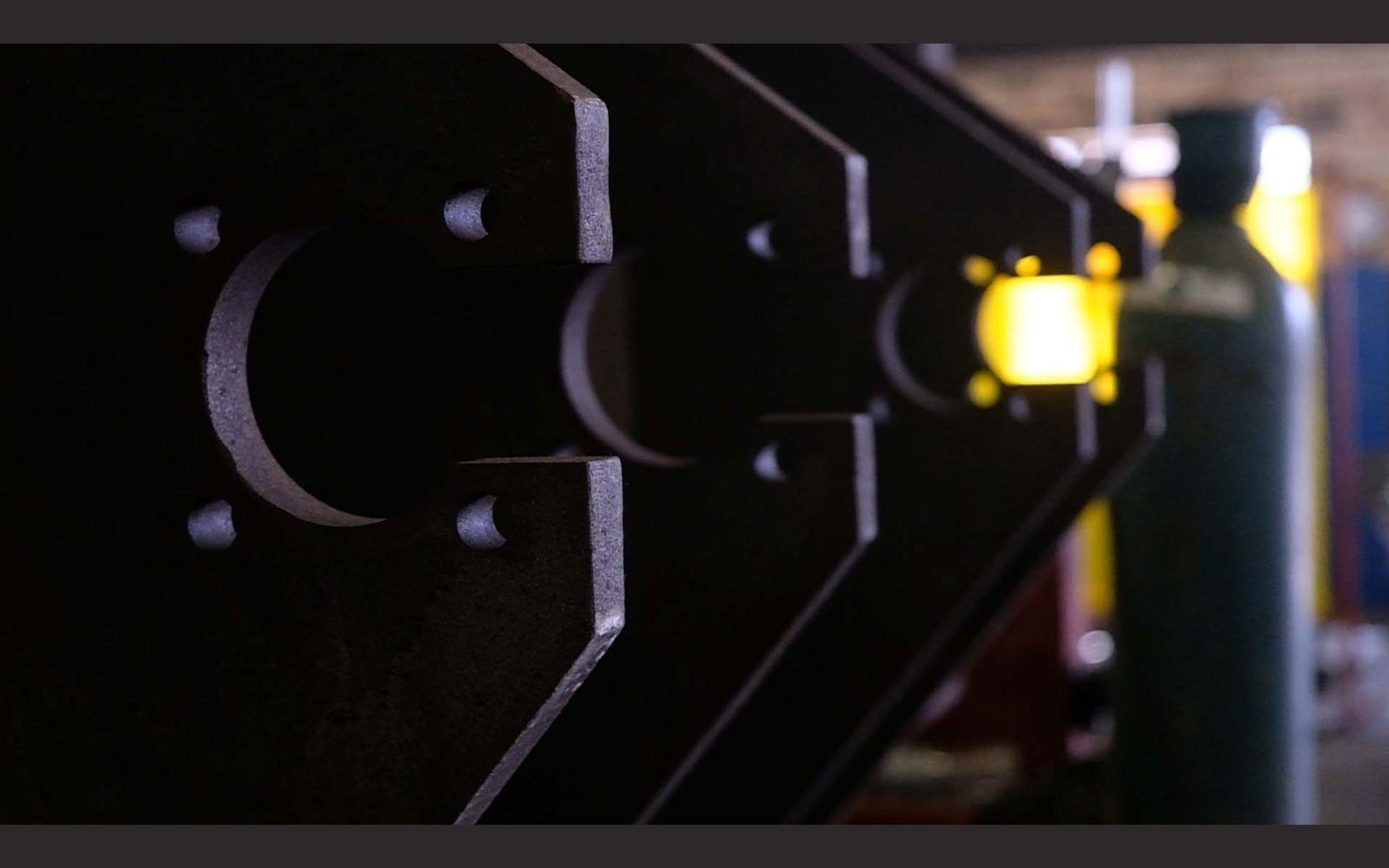 Steel plate with cut-out shapes and gas cylinders behind
