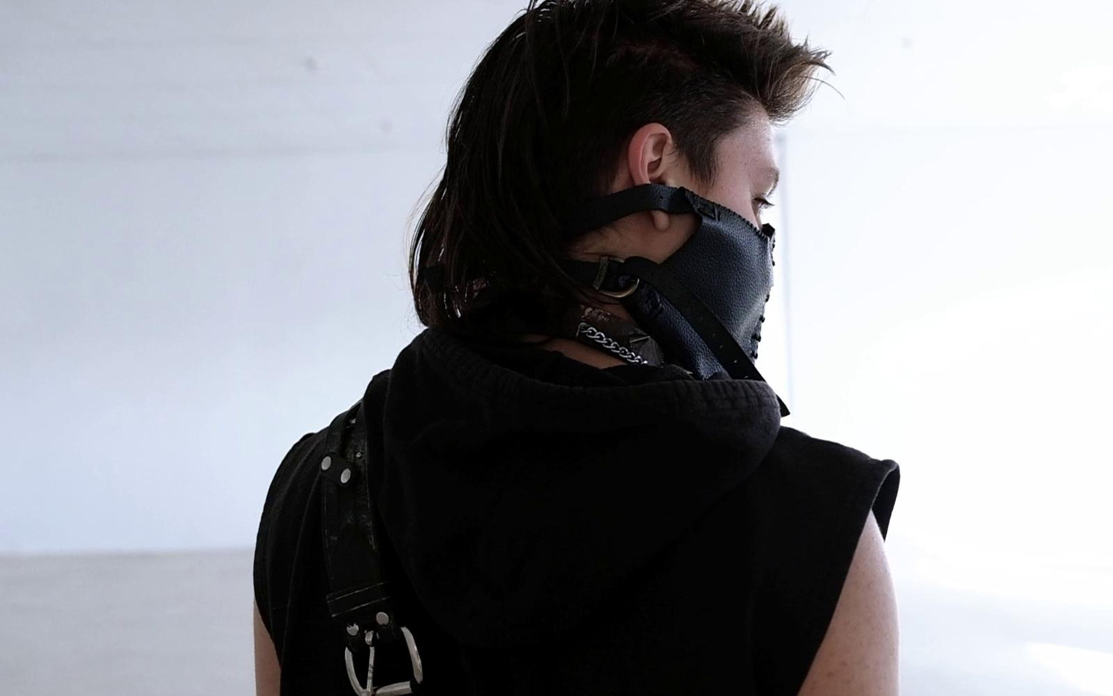 Over-the-shoulder view of the warrior's profile in a black leather mask and strapped hood