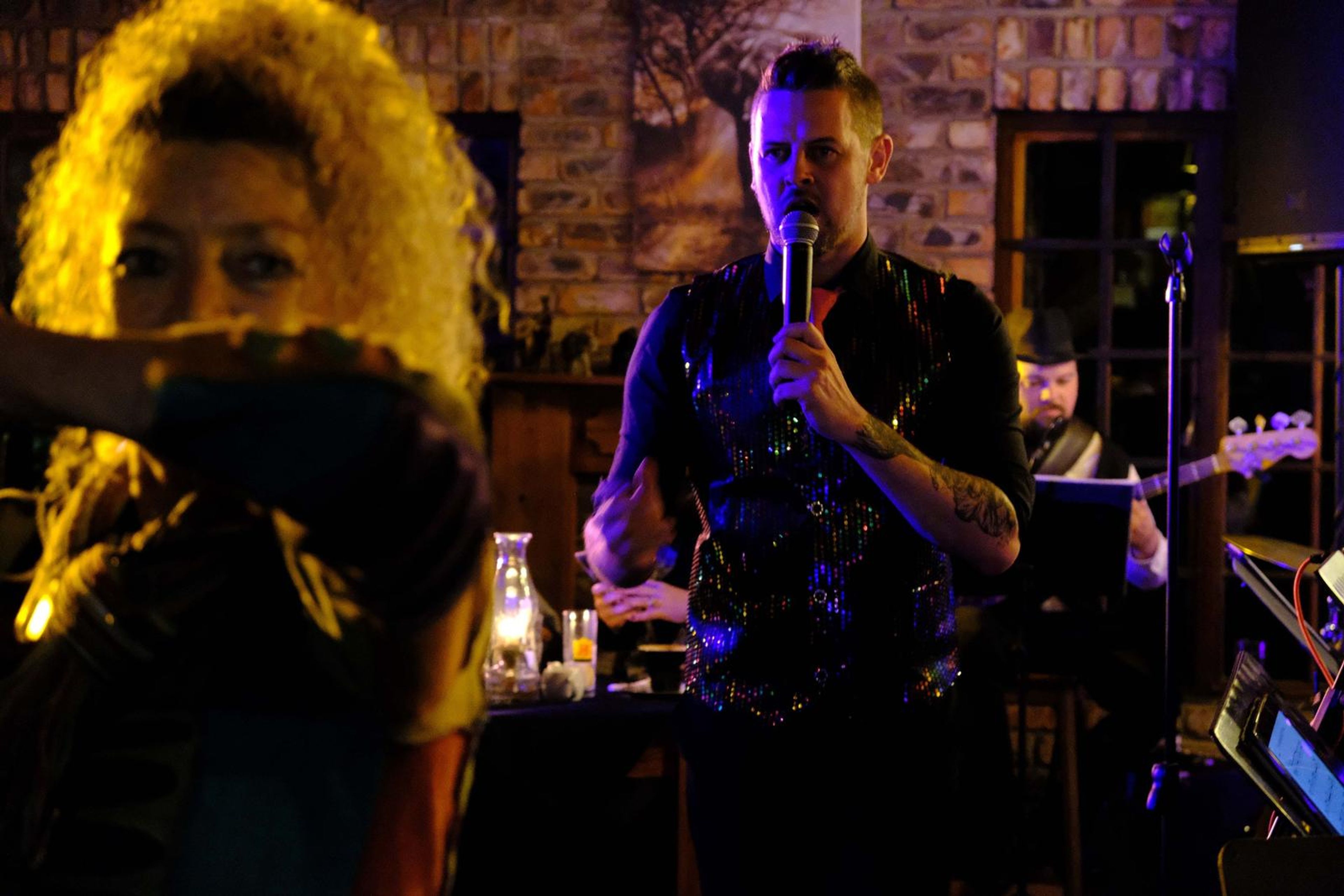 Lead singer reaching a guest with the microphone while the band plays