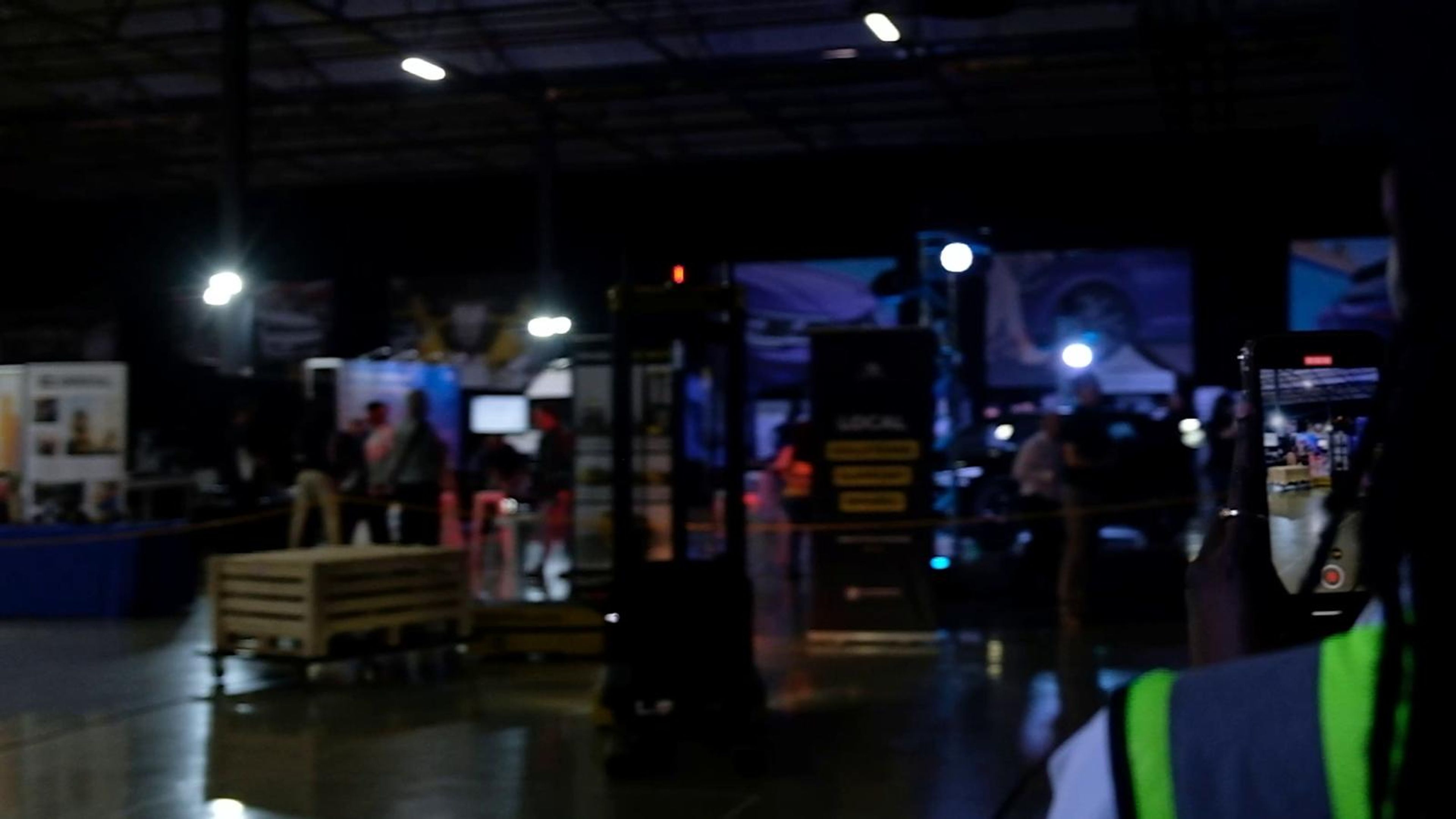 Exhibition stands glowing in the dark expo hall with a forklift in the foreground