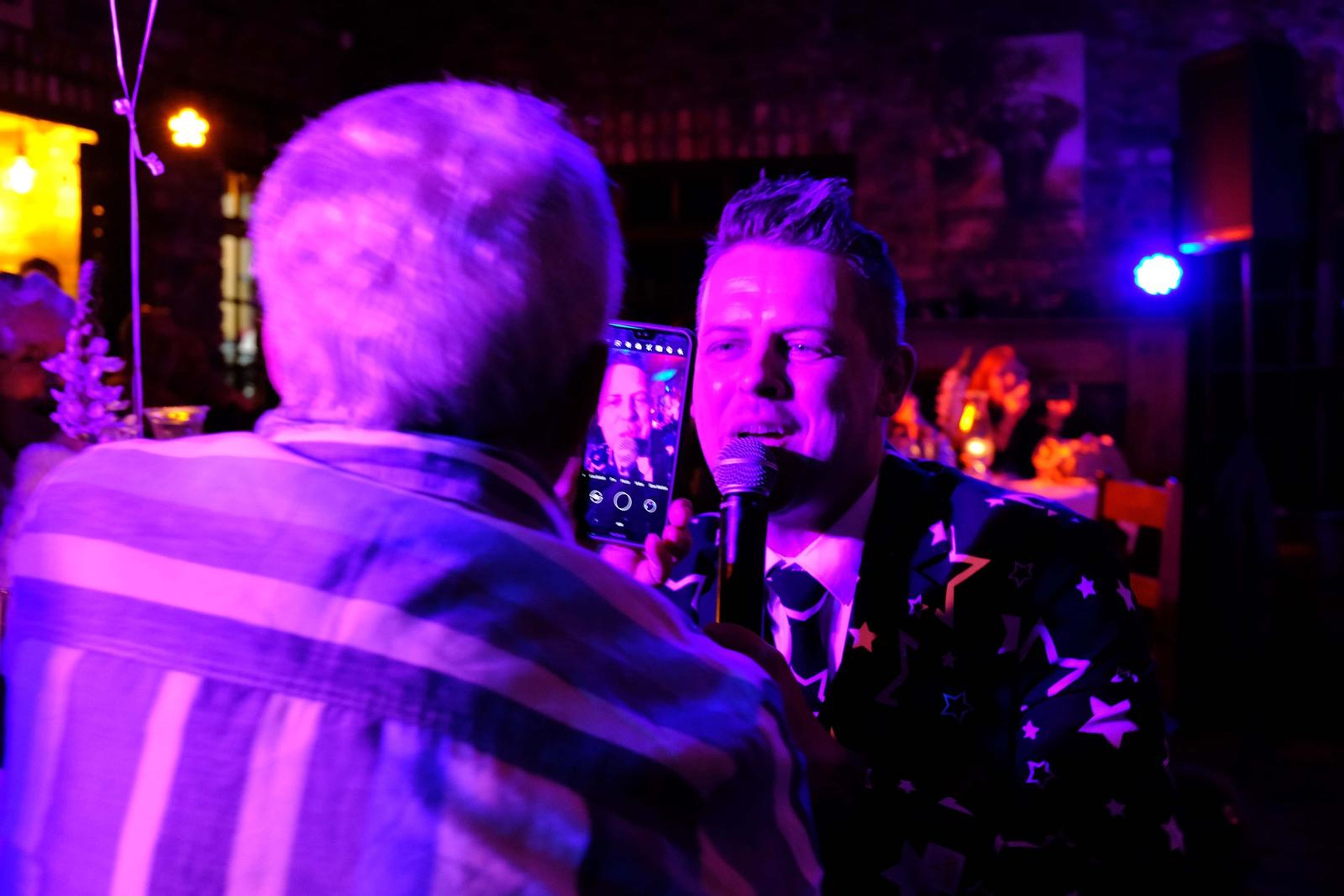 Singer in a star-patterned suit sitting at a guest's table