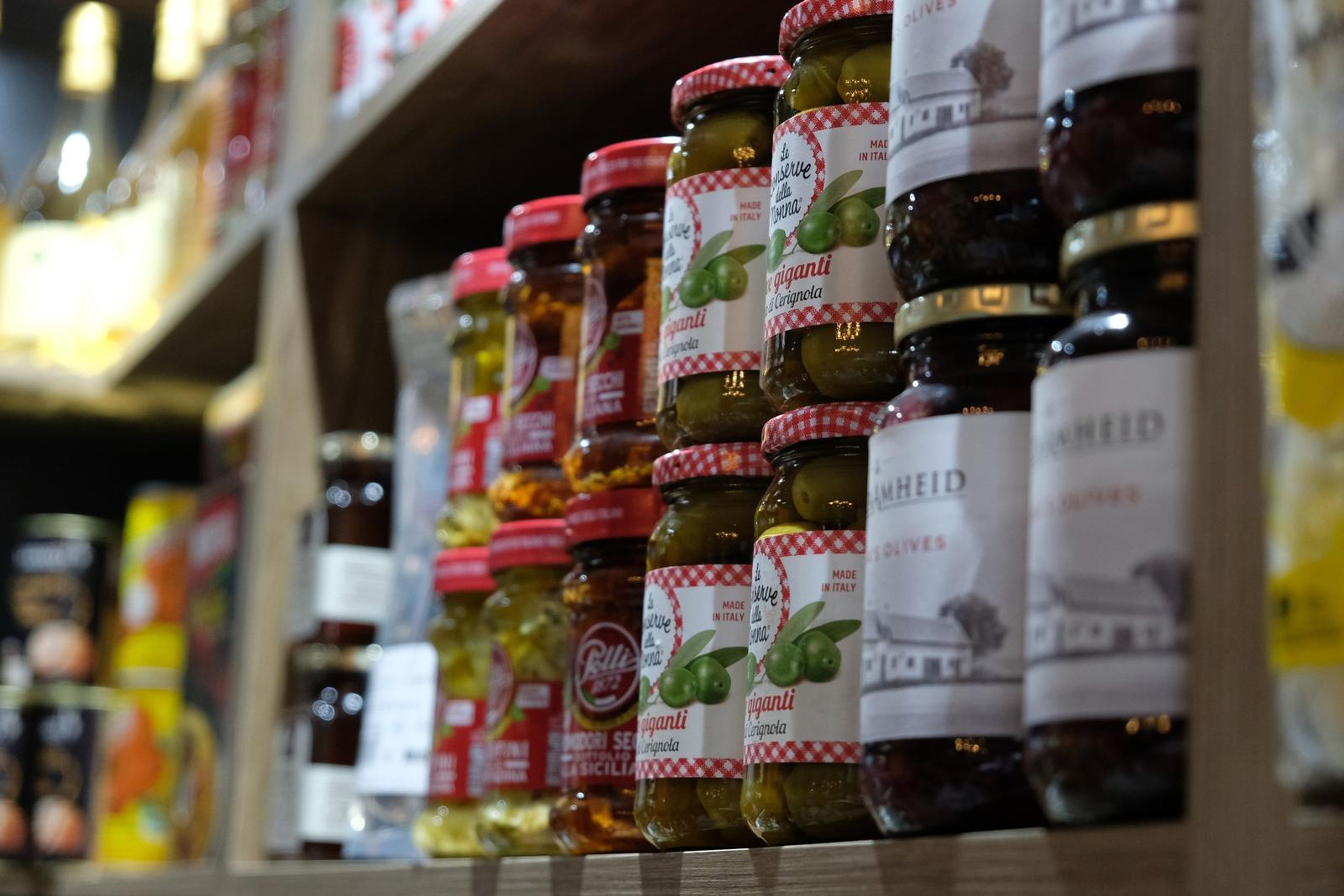 Close-up of preserved olives and jars on a shelf