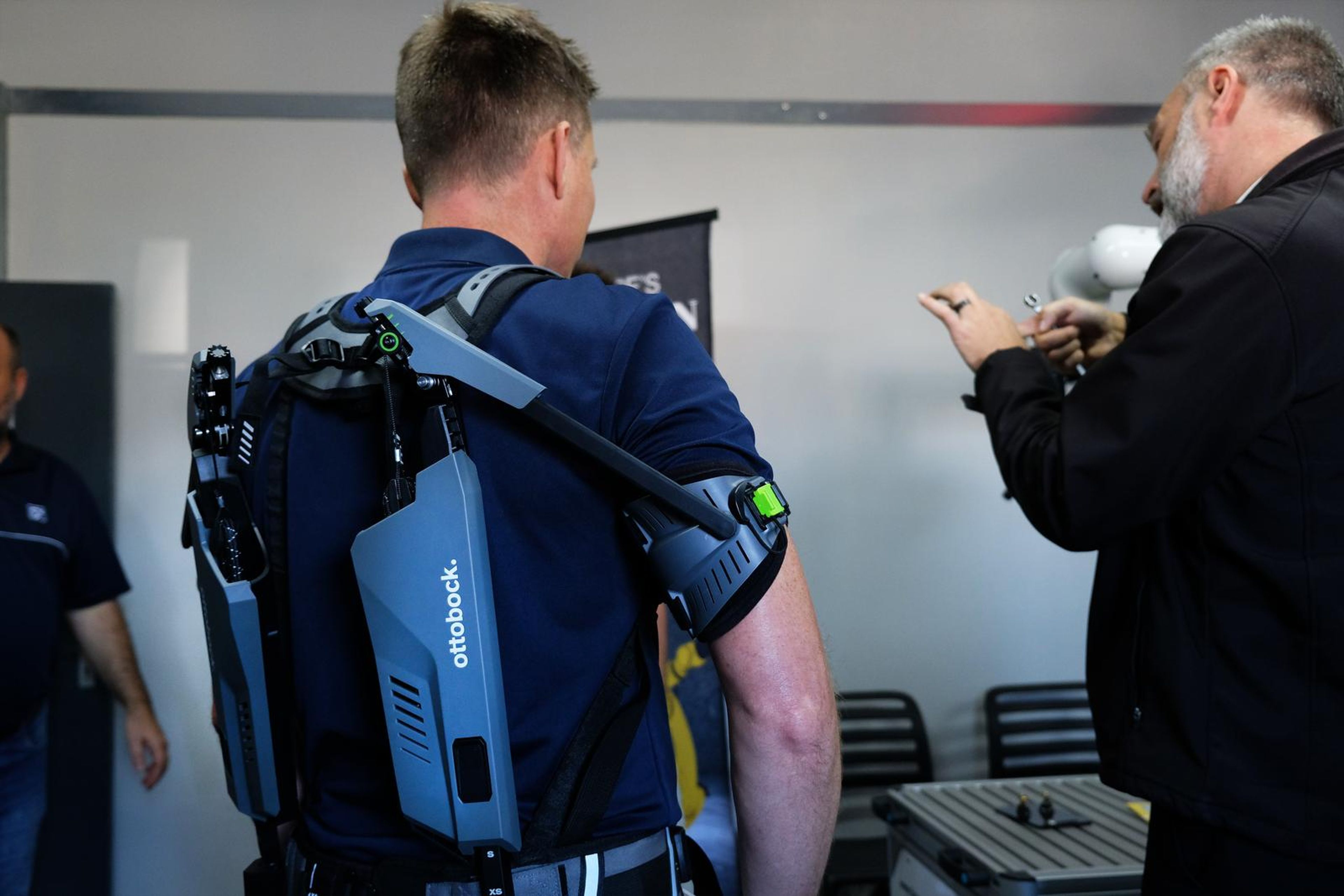 Visitor in the exoskeleton with people in conversation behind