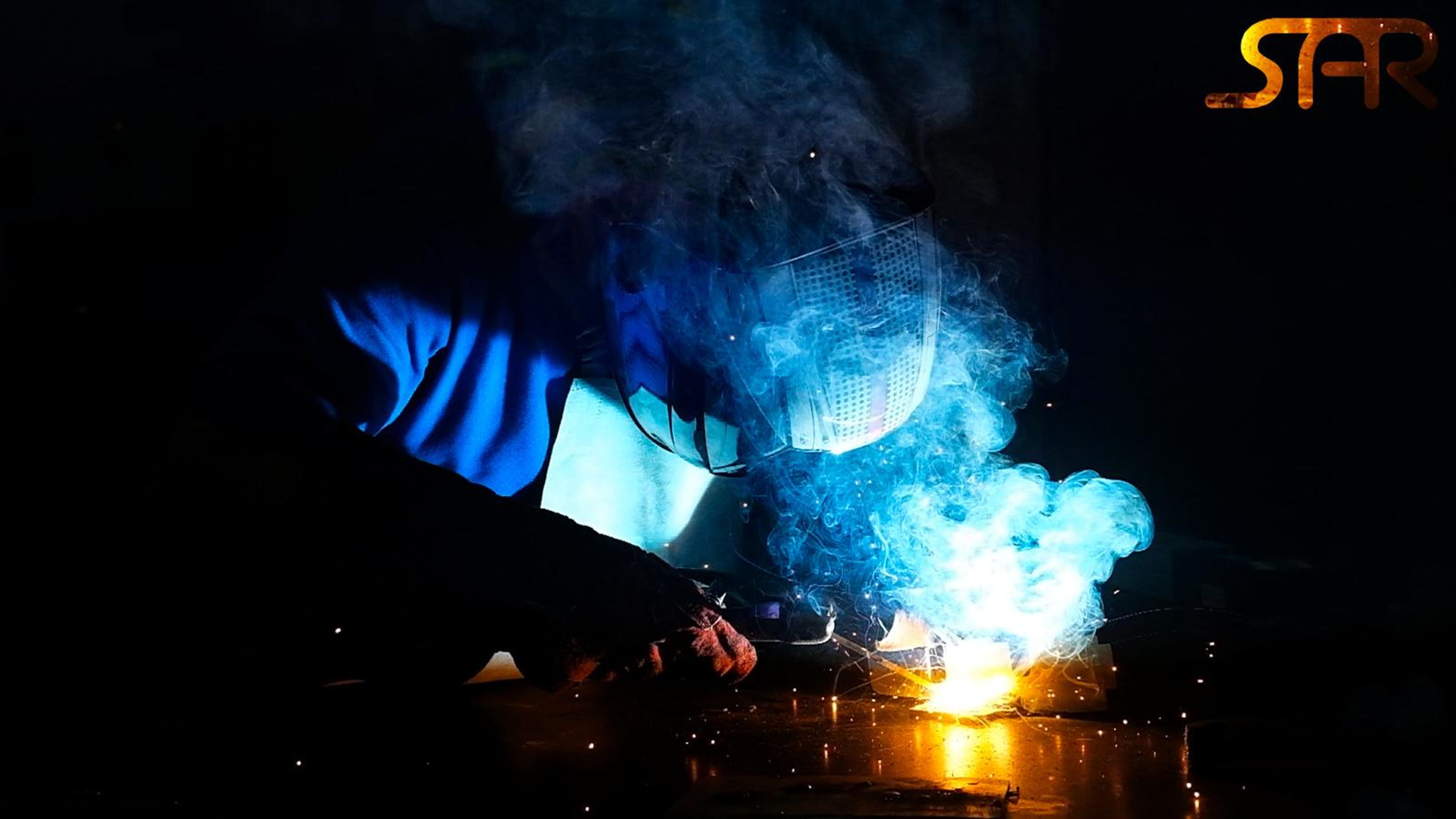 Welding arc on a dark background with the SAR logo in an orange glow at the top right