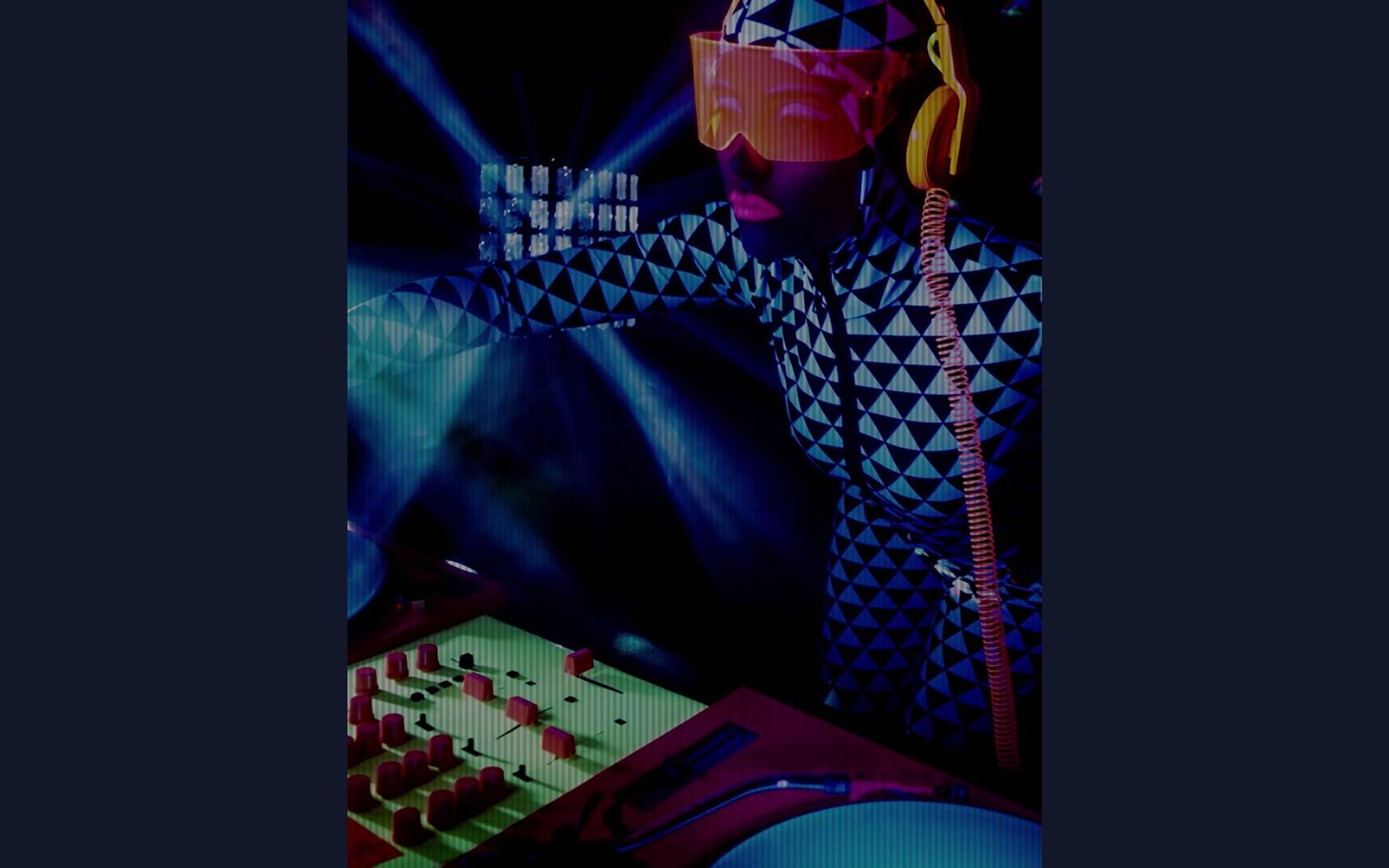 Dancer in a triangle-patterned bodysuit with an orange visor and yellow headphones beside a mixing desk