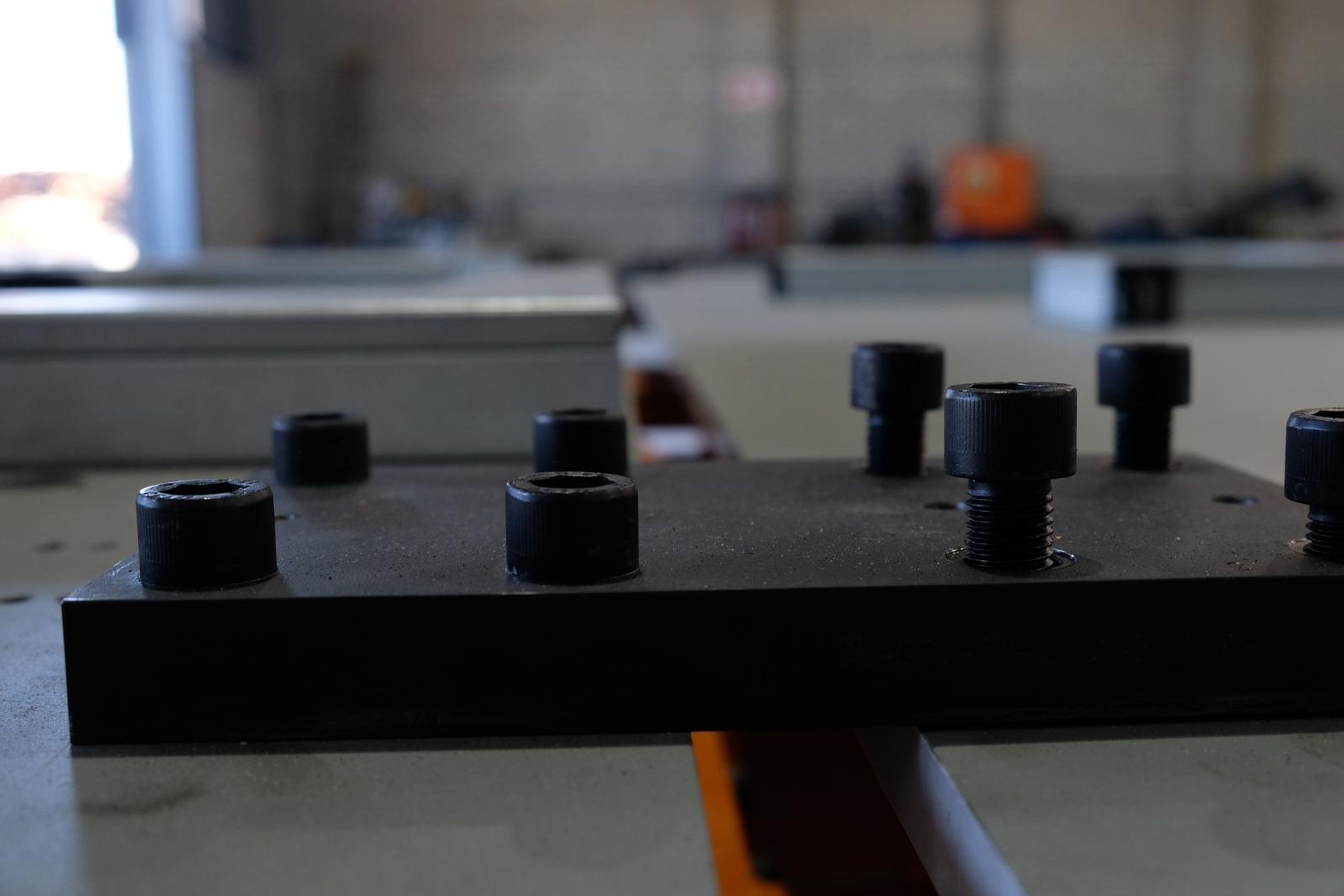 Black bolts and a steel plate in soft focus