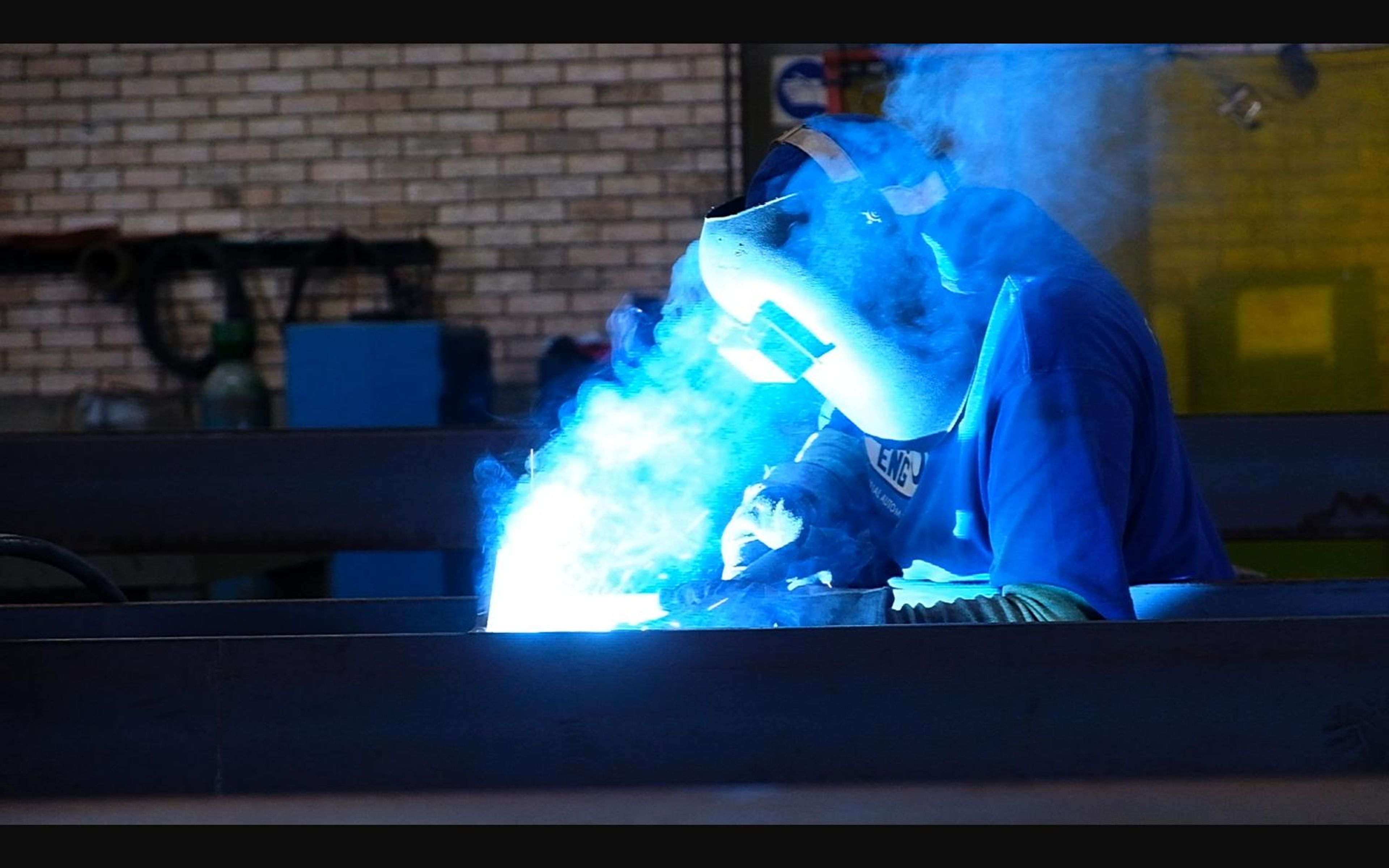 Welder lit by the blue glow of the arc