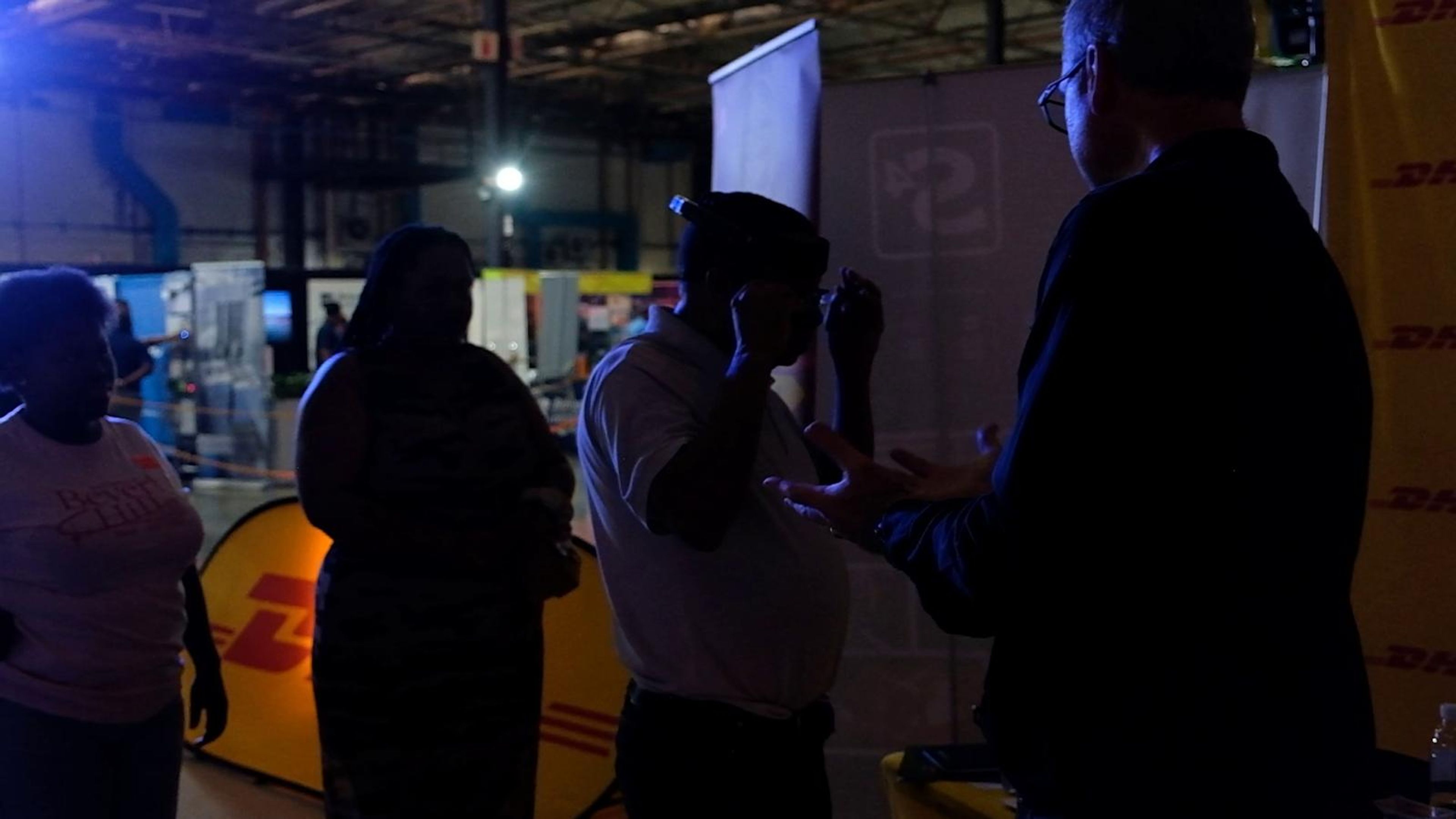 Visitors talking at a stand beside a yellow DHL banner