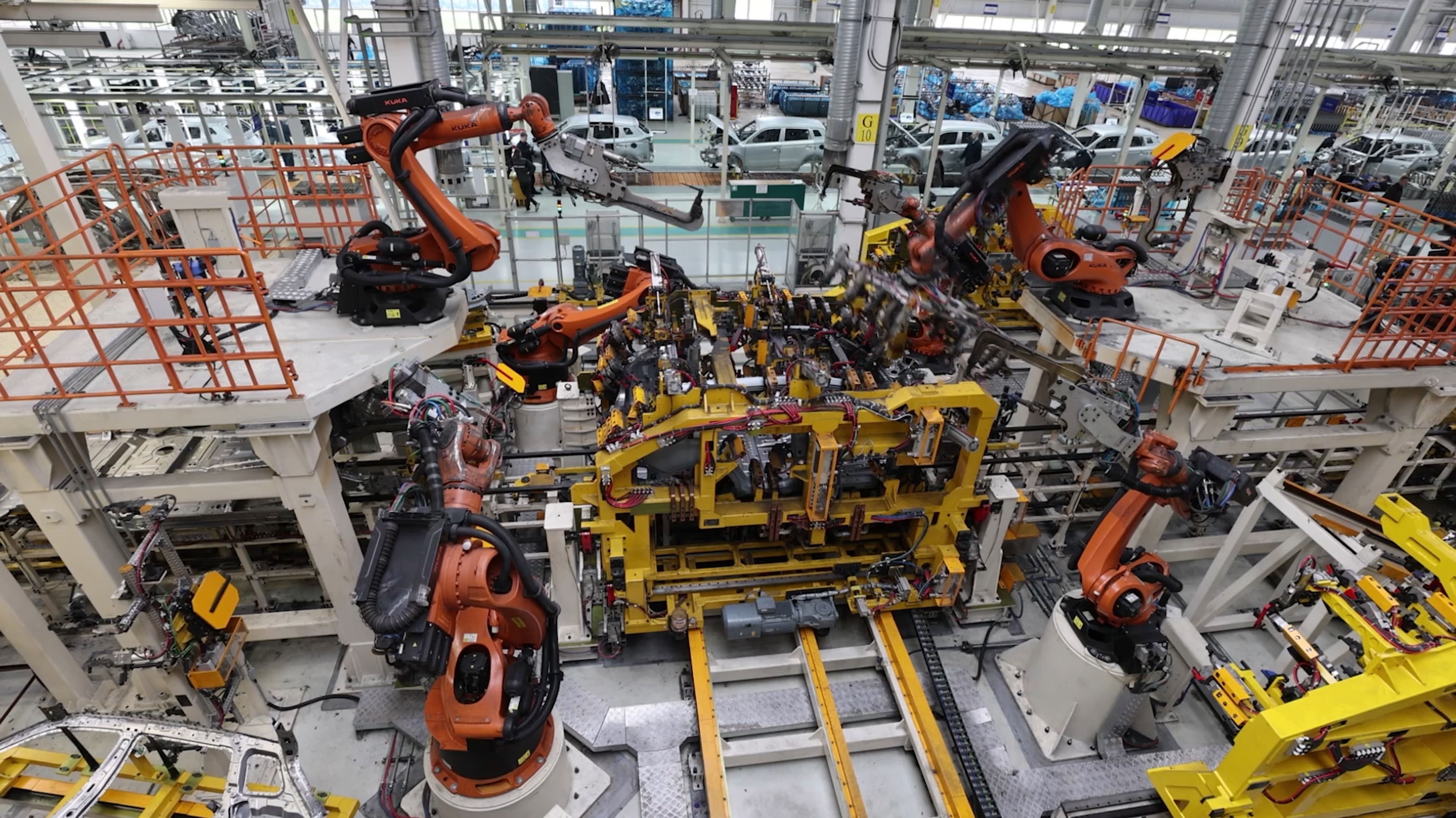 Overhead view of a car assembly line with orange robots