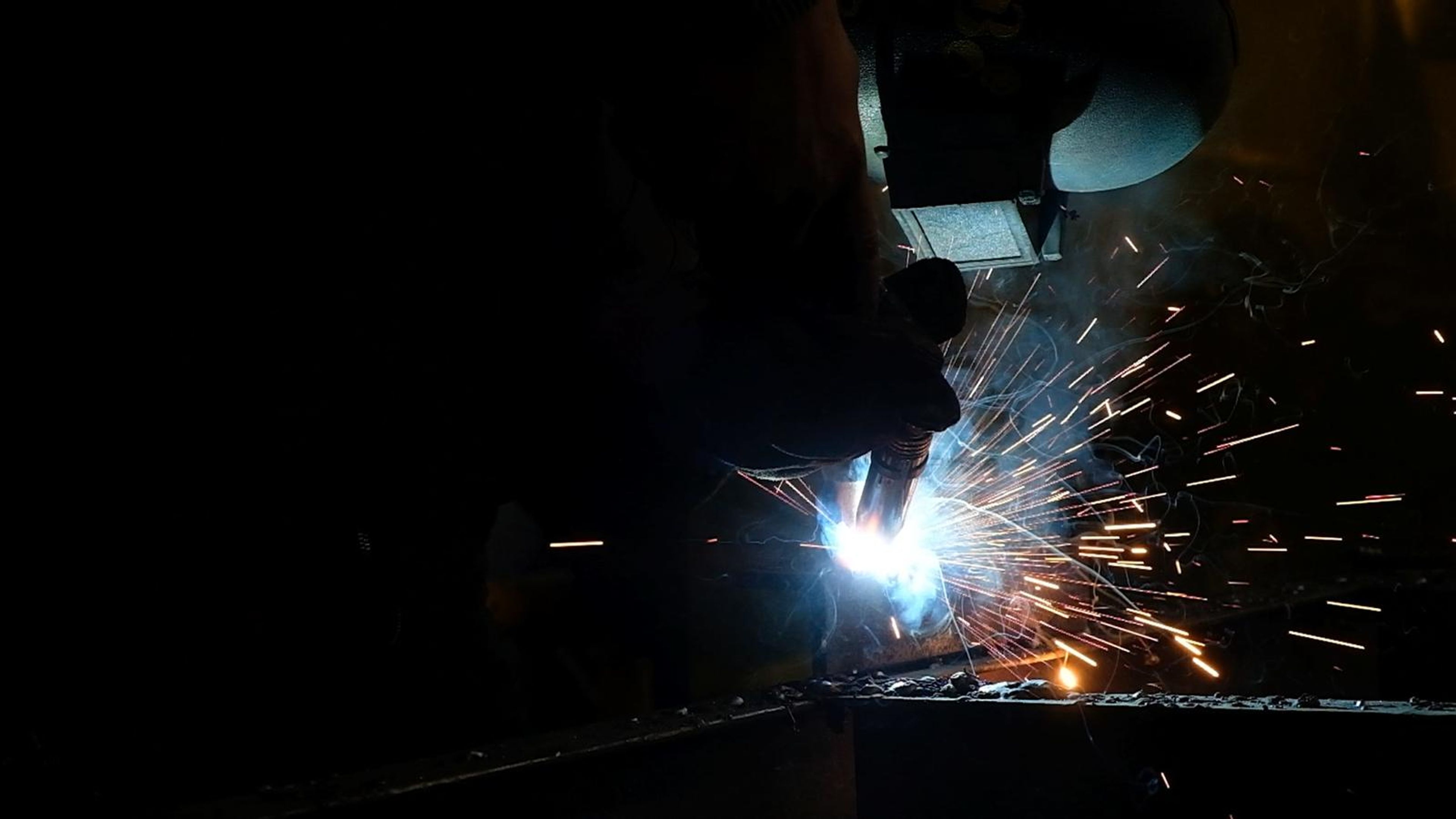 Welding arc flaring with orange sparks in the dark
