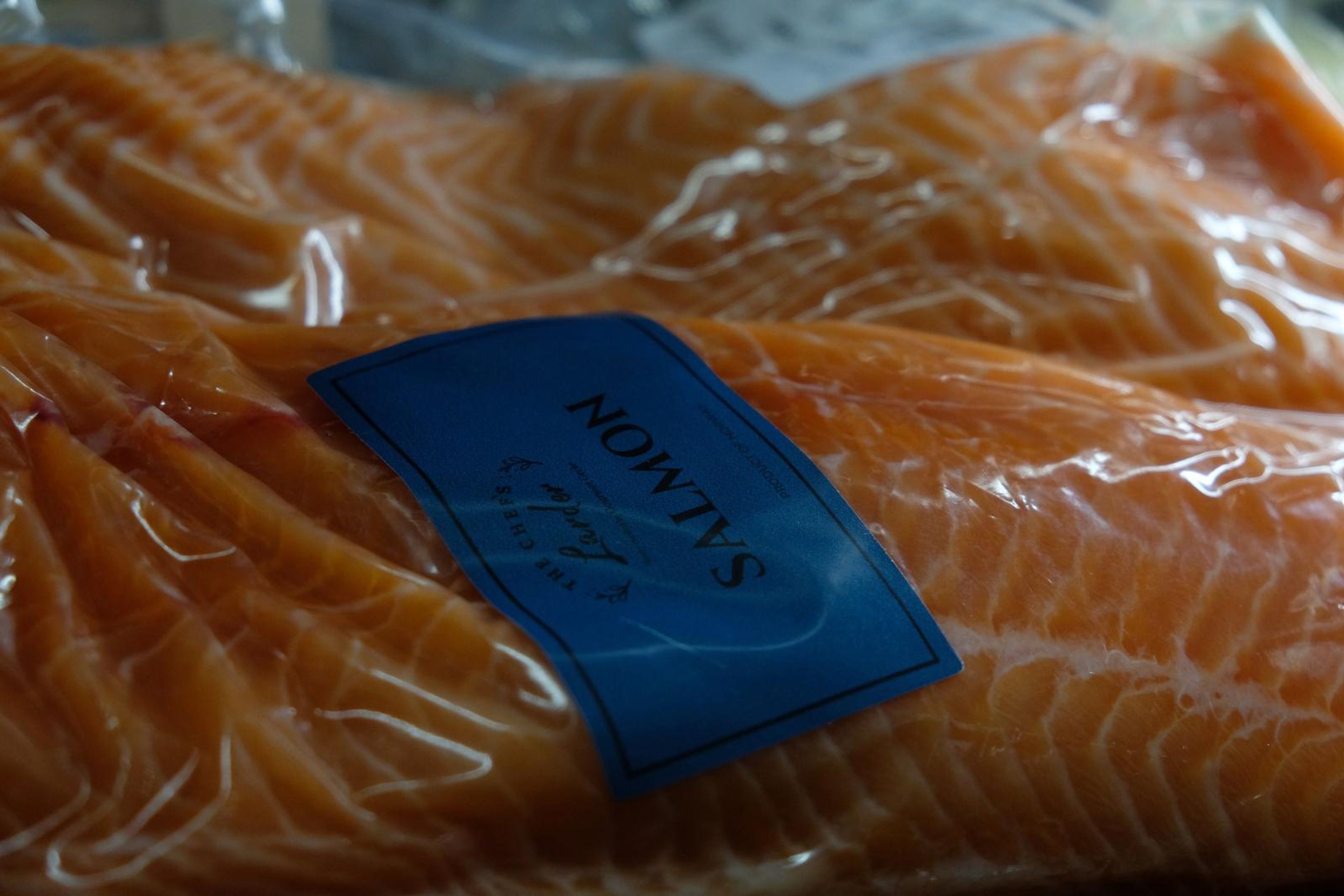 Fresh salmon fillets in vacuum packs with a blue label