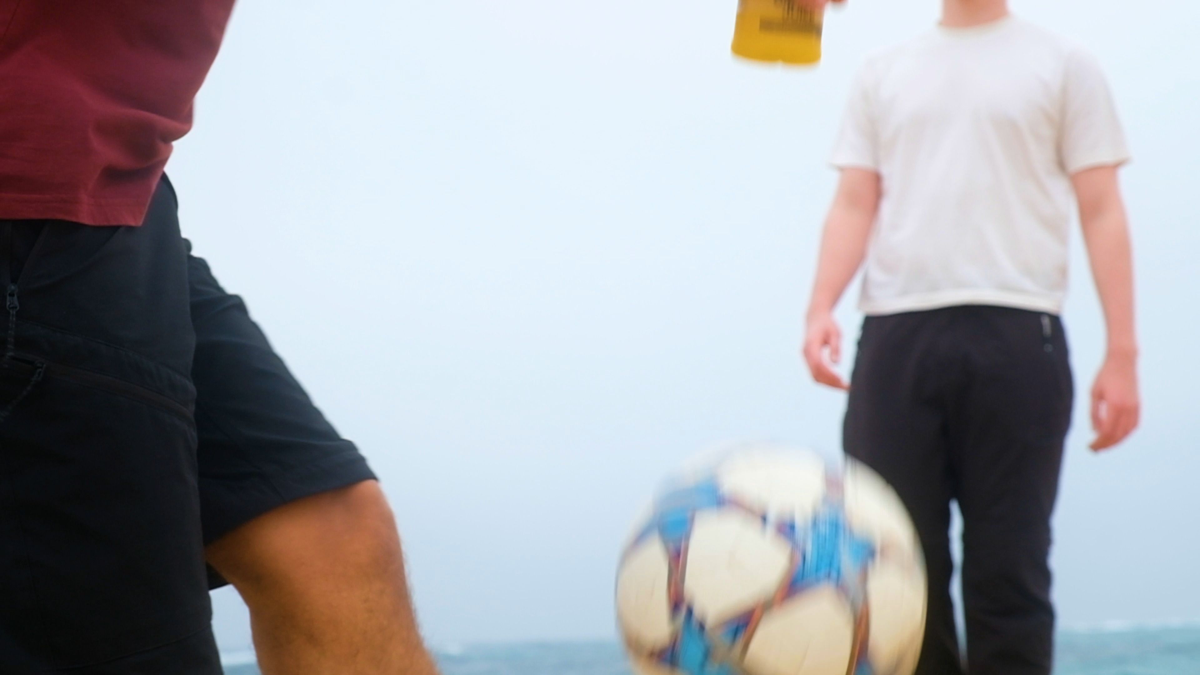 Football on the beach with a person standing behind it
