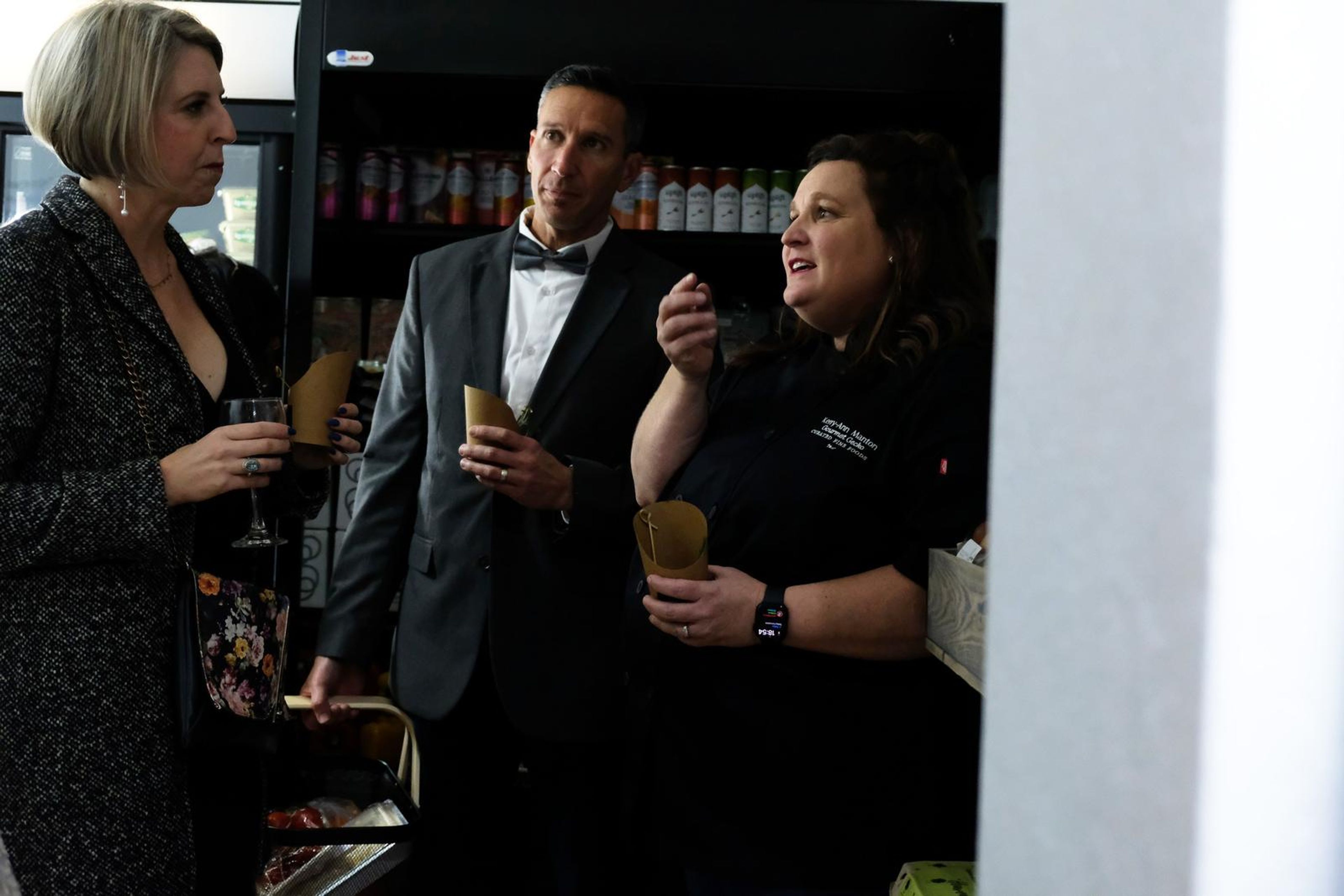 Three guests chatting behind the counter holding drinks