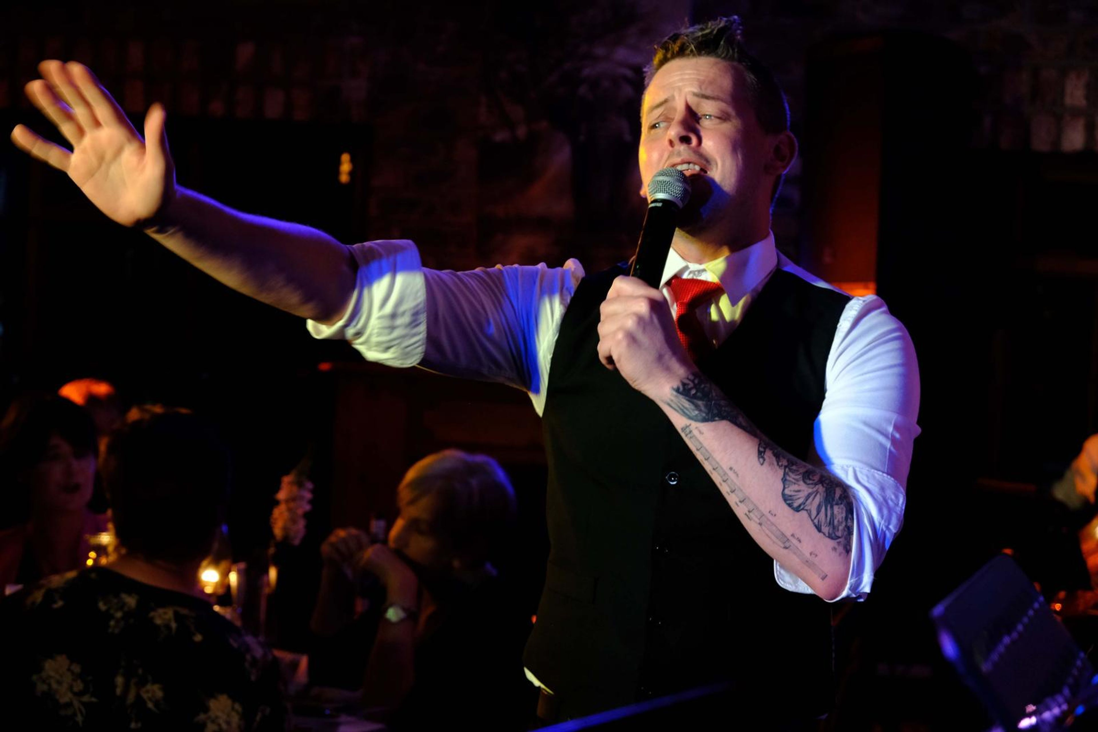 Singer with his arms wide as he holds a long note