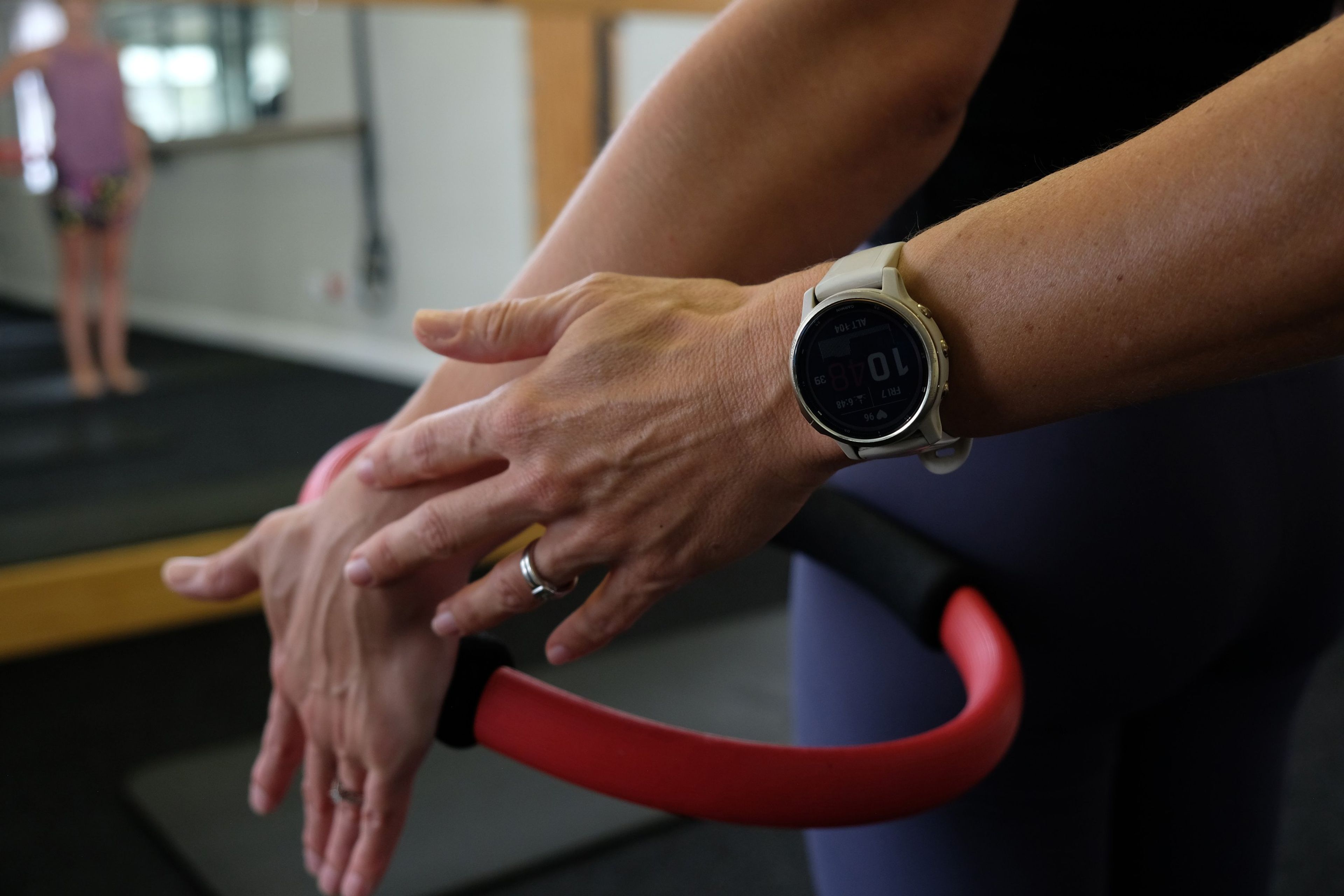 Close-up of hands pressing a red Pilates ring