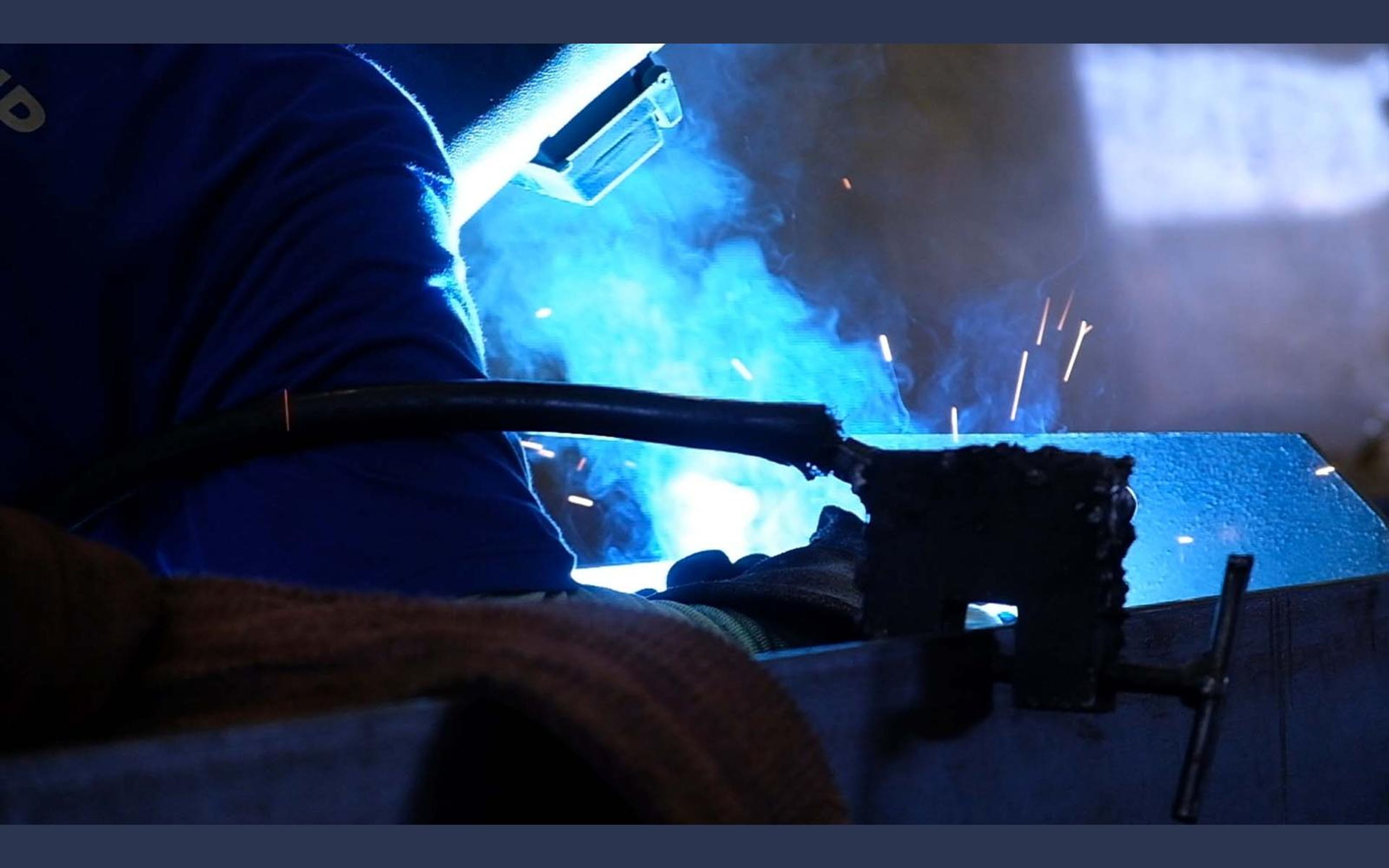 Welder in a mask working in bright blue arc light