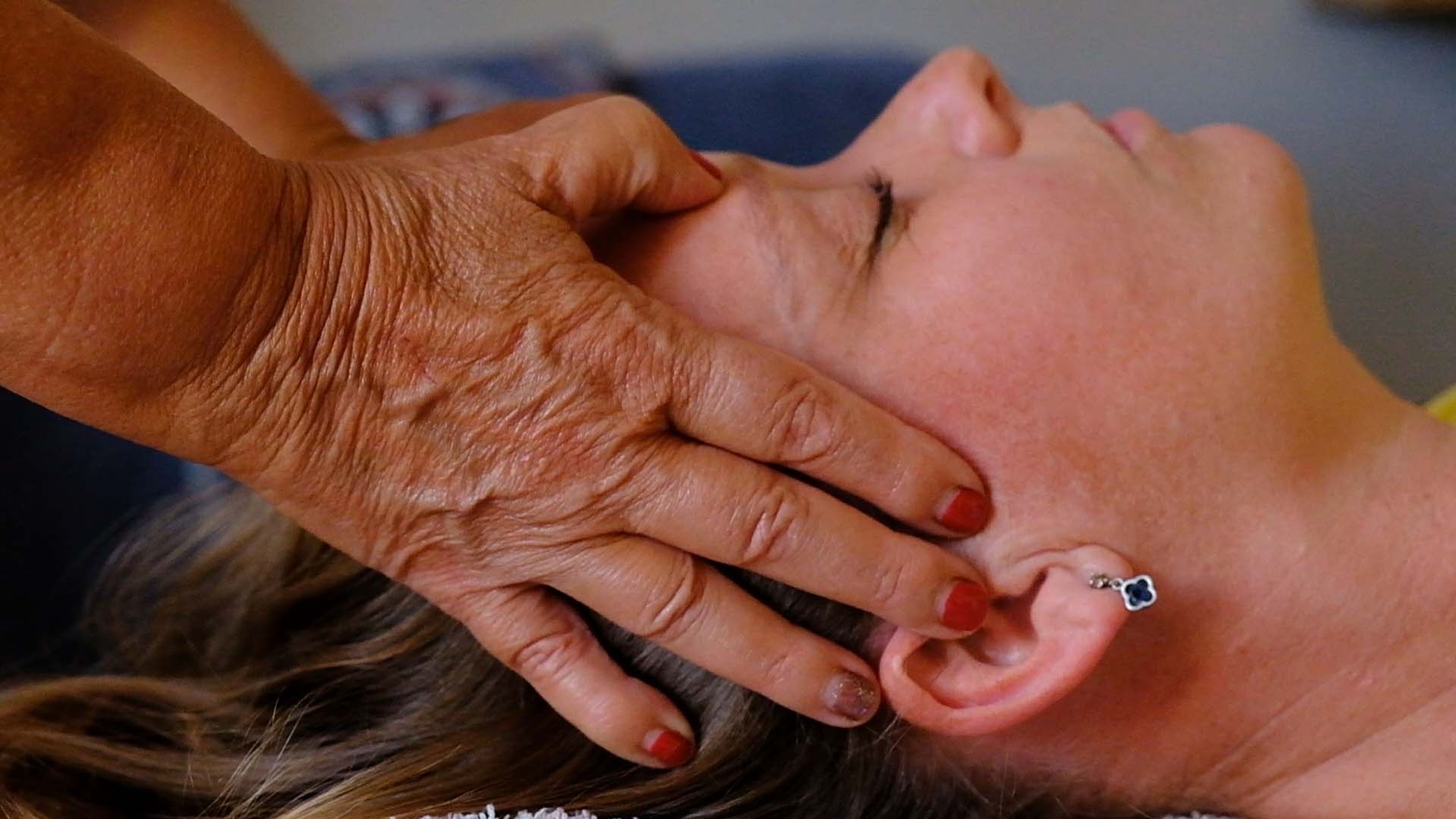 A therapist's hands on a client's face during a treatment
