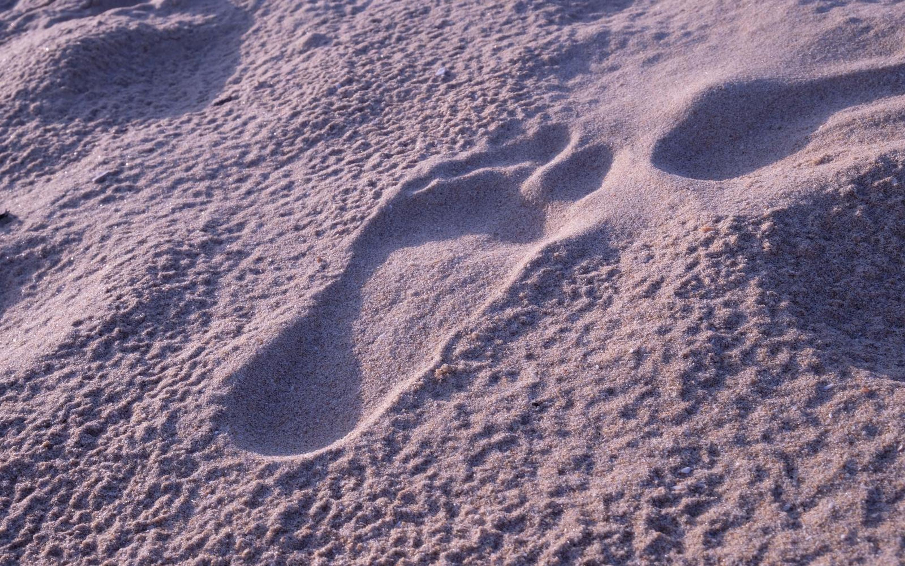 Pair of footprints on a sloping sand surface with fine grain texture