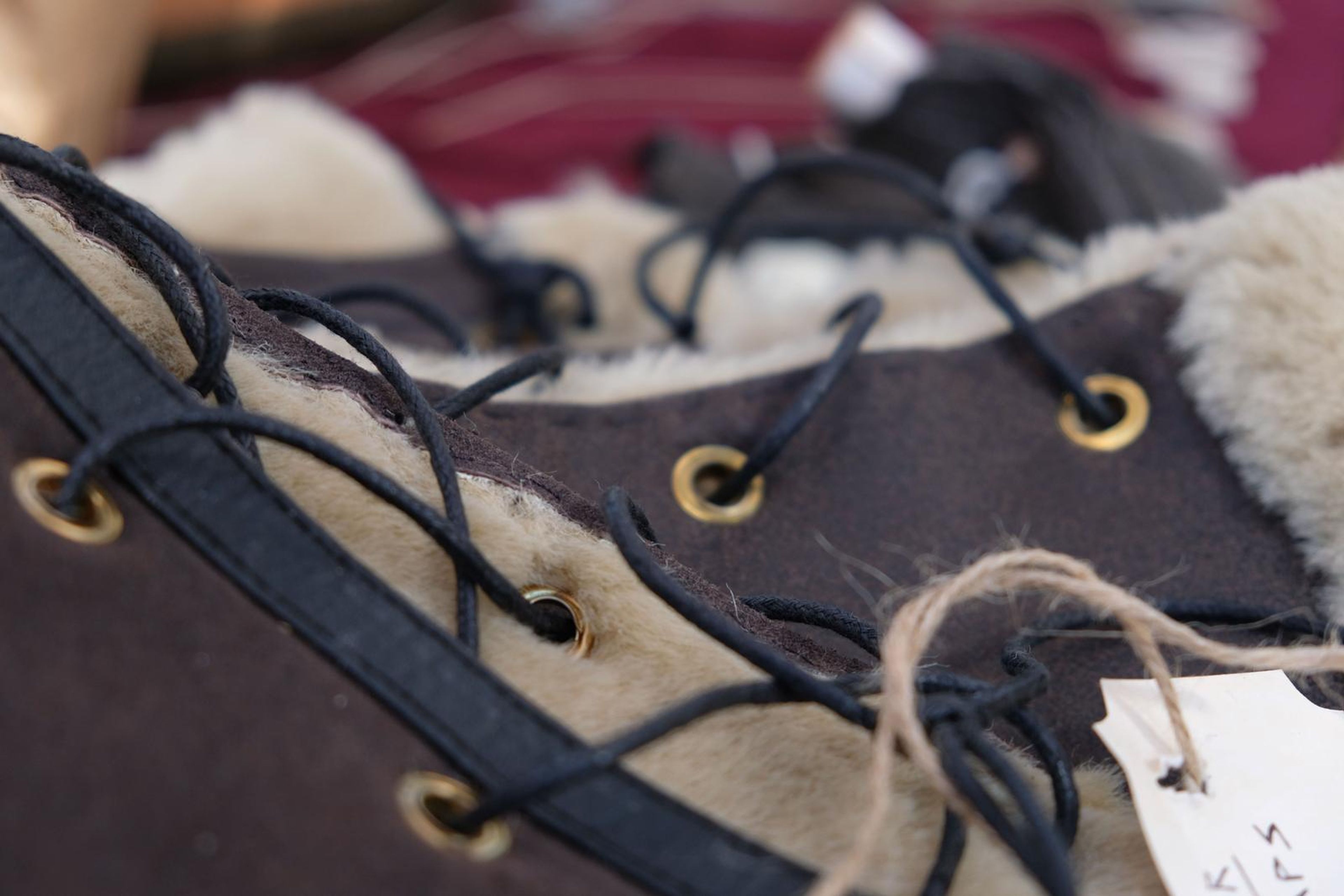 Close-up of fur-lined leather arm wraps with eyelets and black lacing