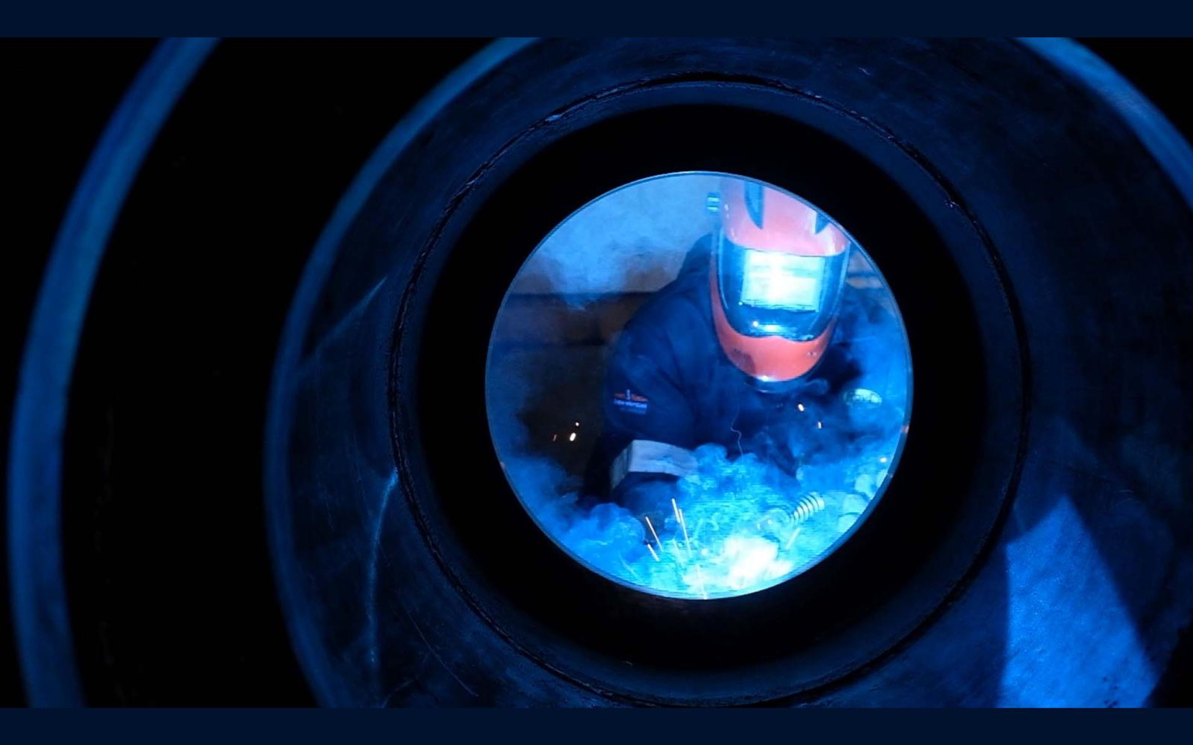Welder framed by a circular steel tube while welding