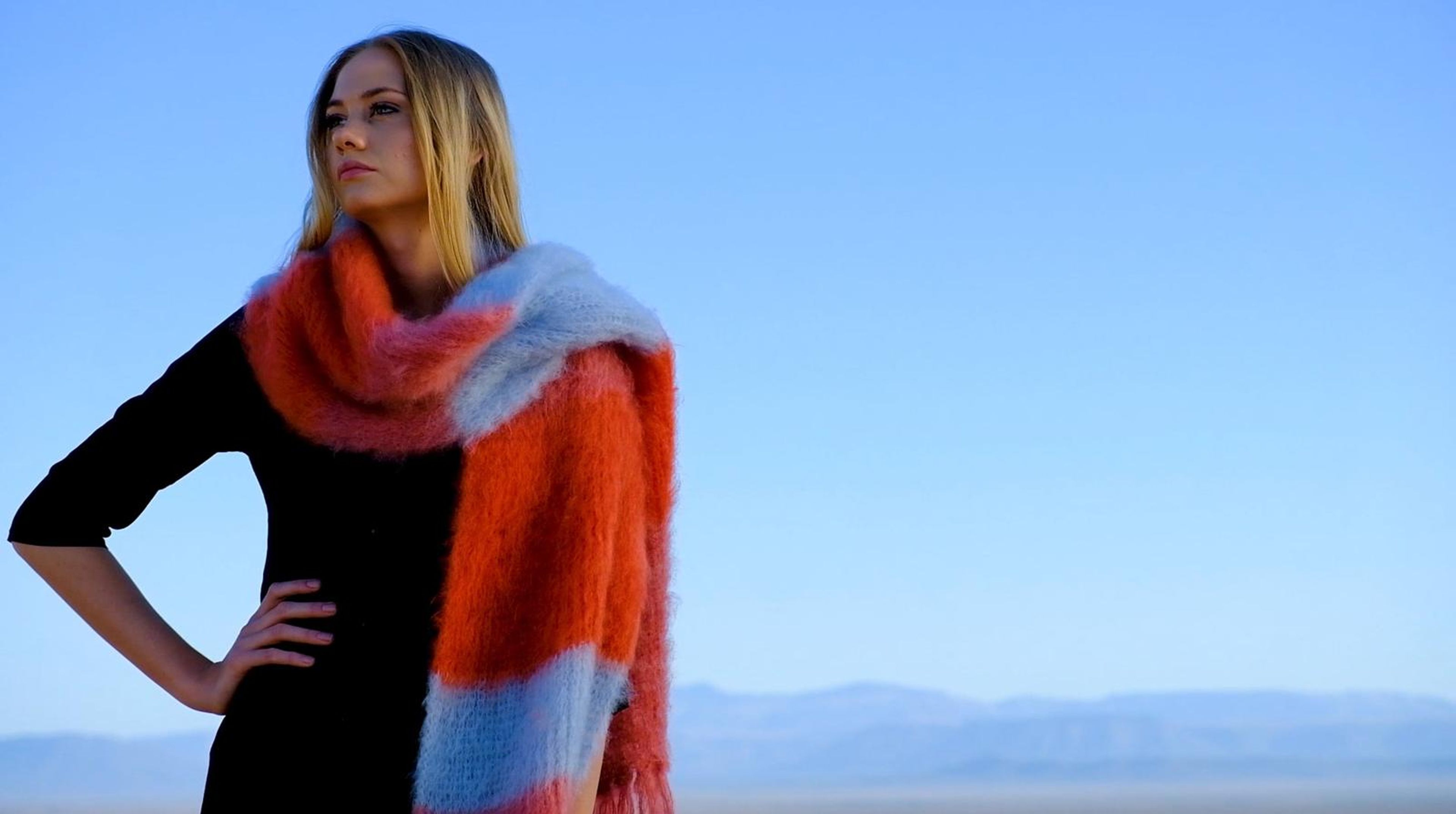 Model in a red, orange and grey mohair wrap with a hand on her hip