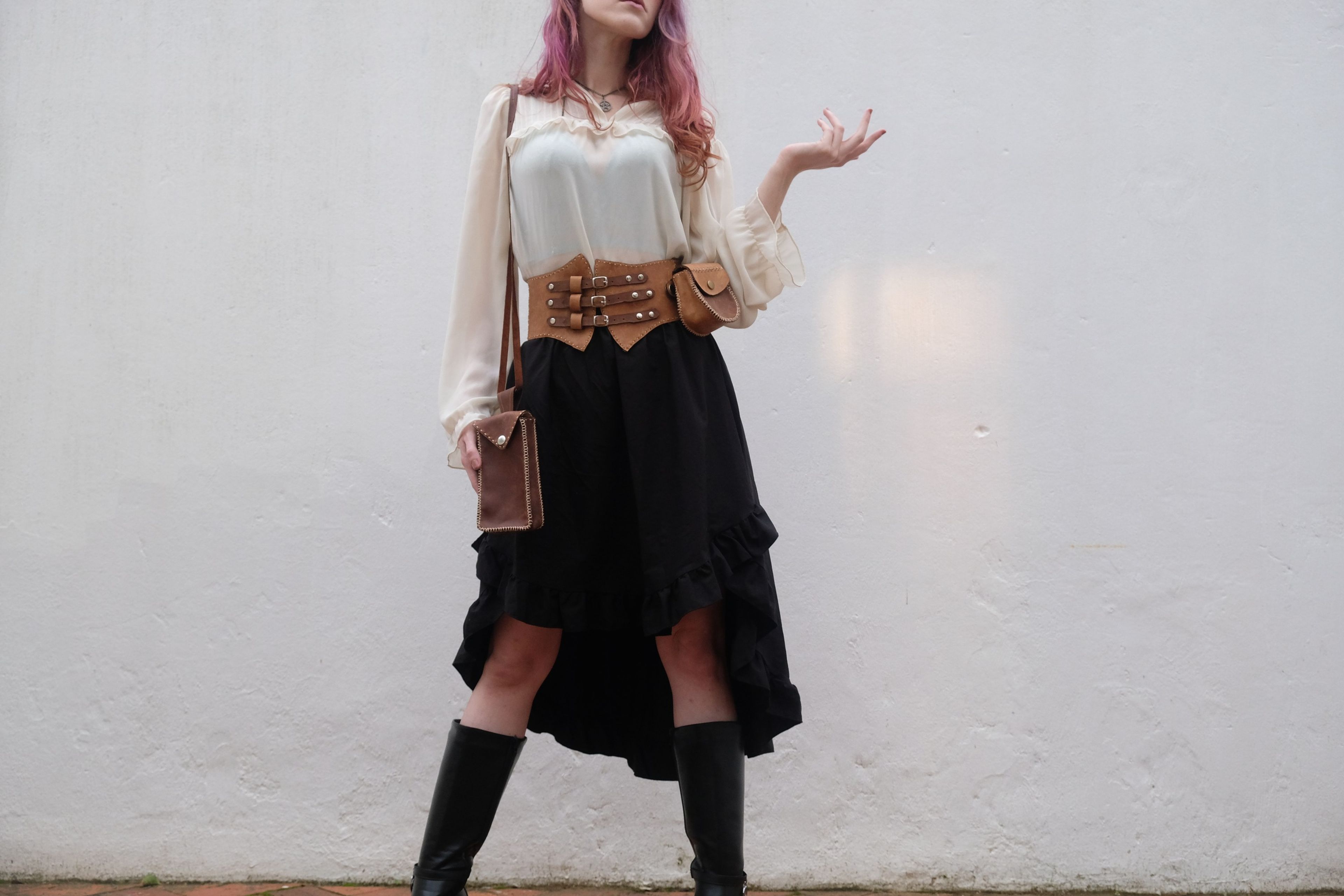 Full-length view of a woman in boots, a black ruffled skirt and a leather corset belt