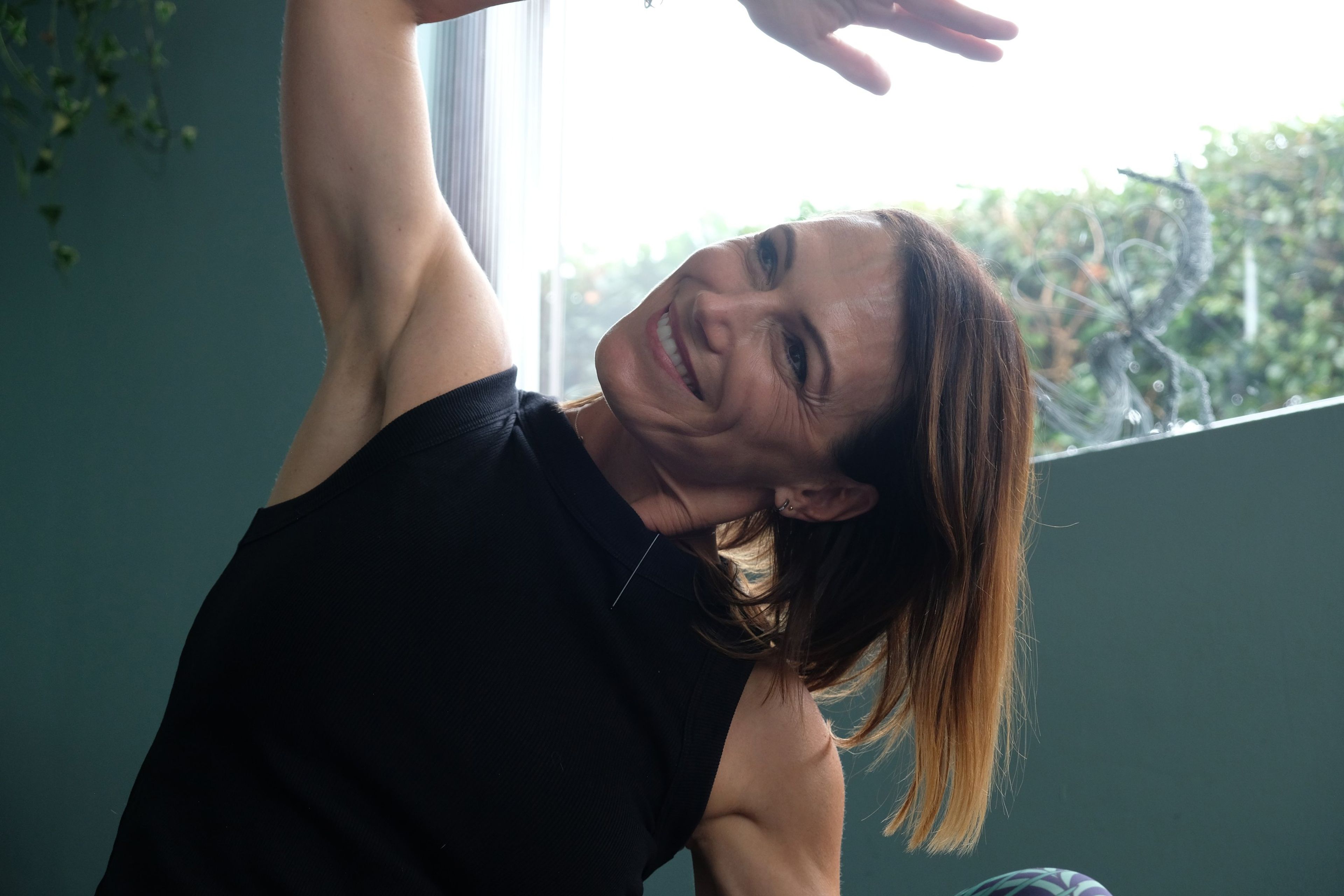 Close-up of an instructor smiling as she stretches one arm overhead in a side bend