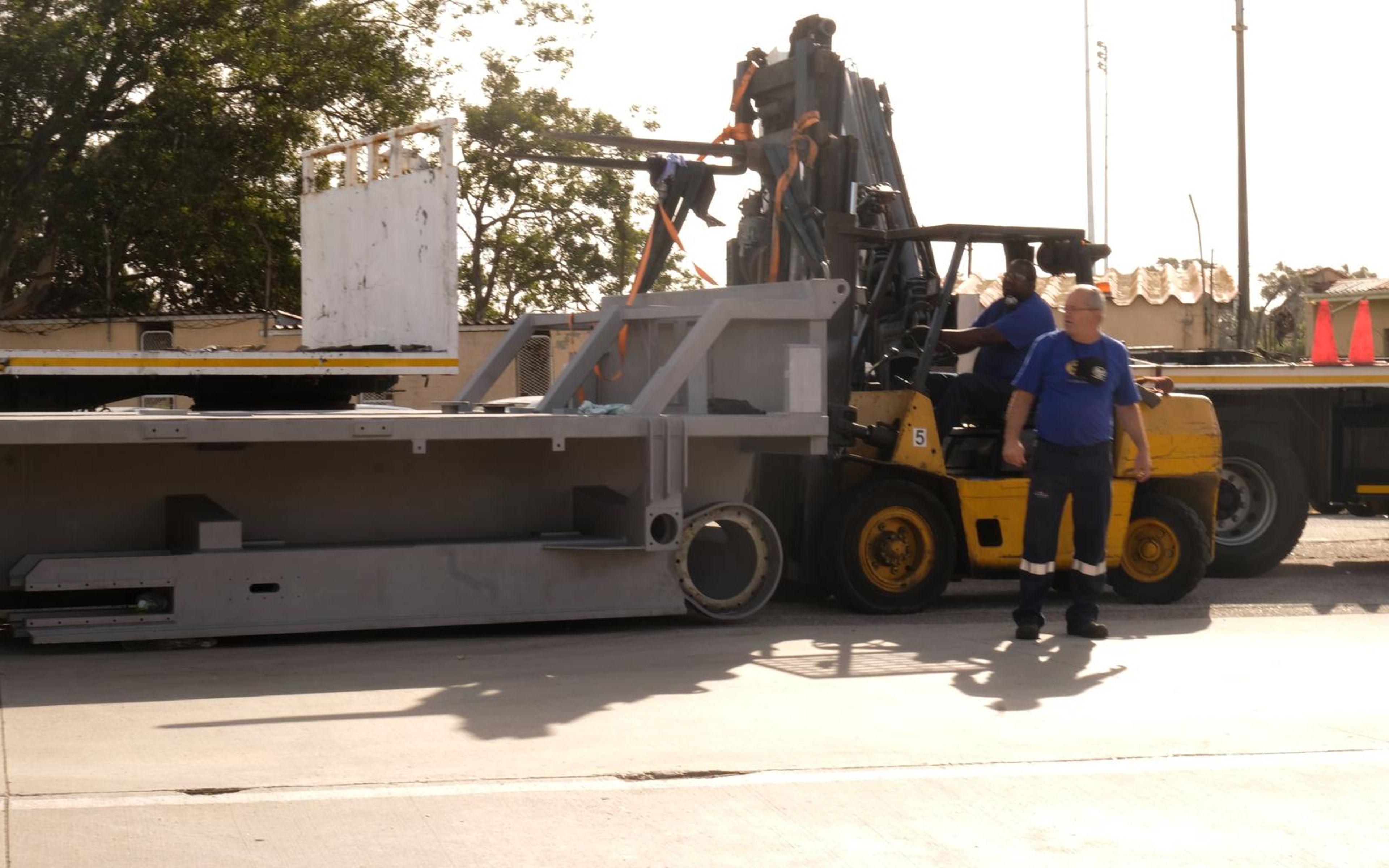 Grey steel chassis section on a trailer with a forklift and driver