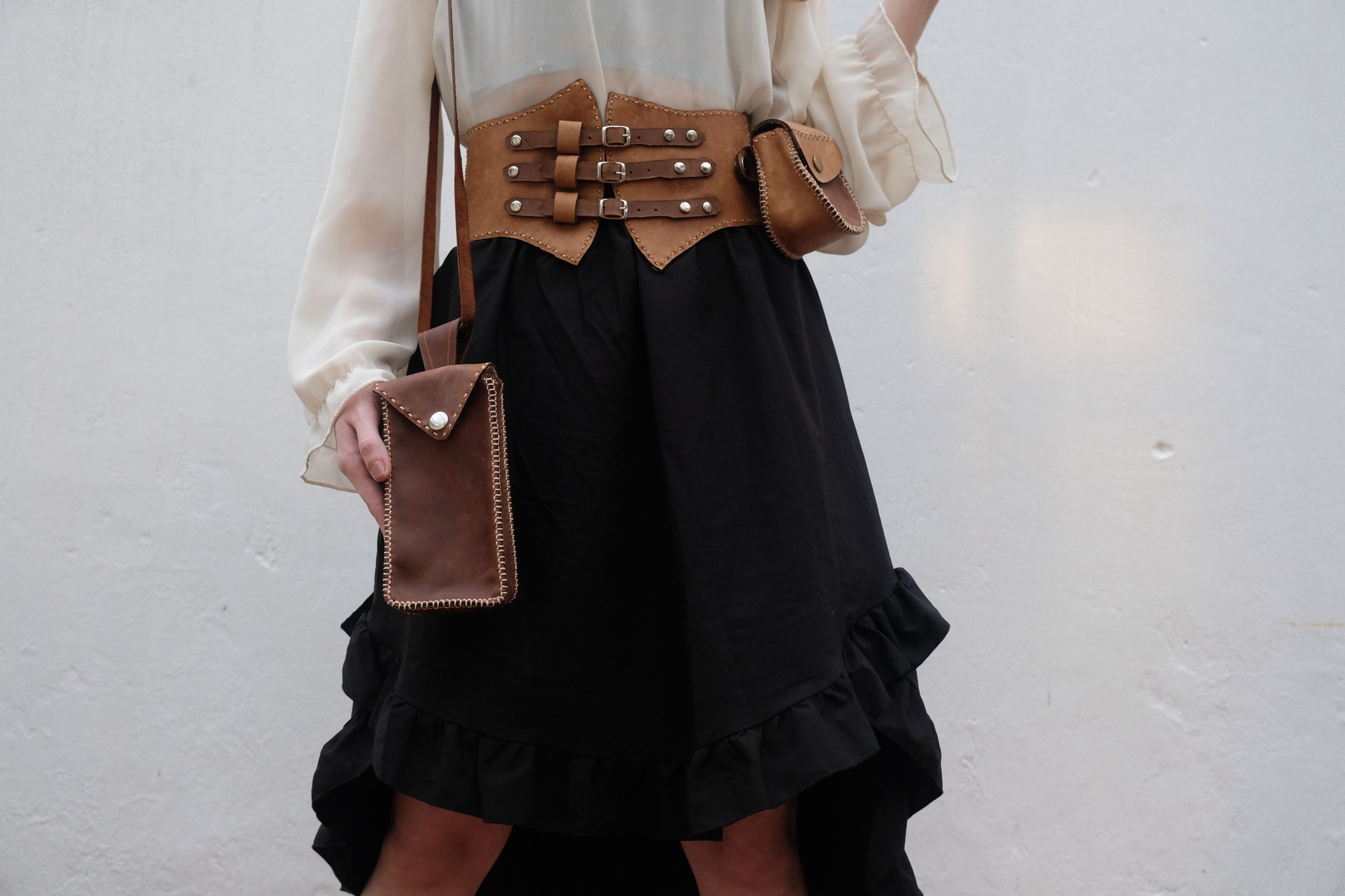 Woman in a leather corset belt with a shoulder strap and bag