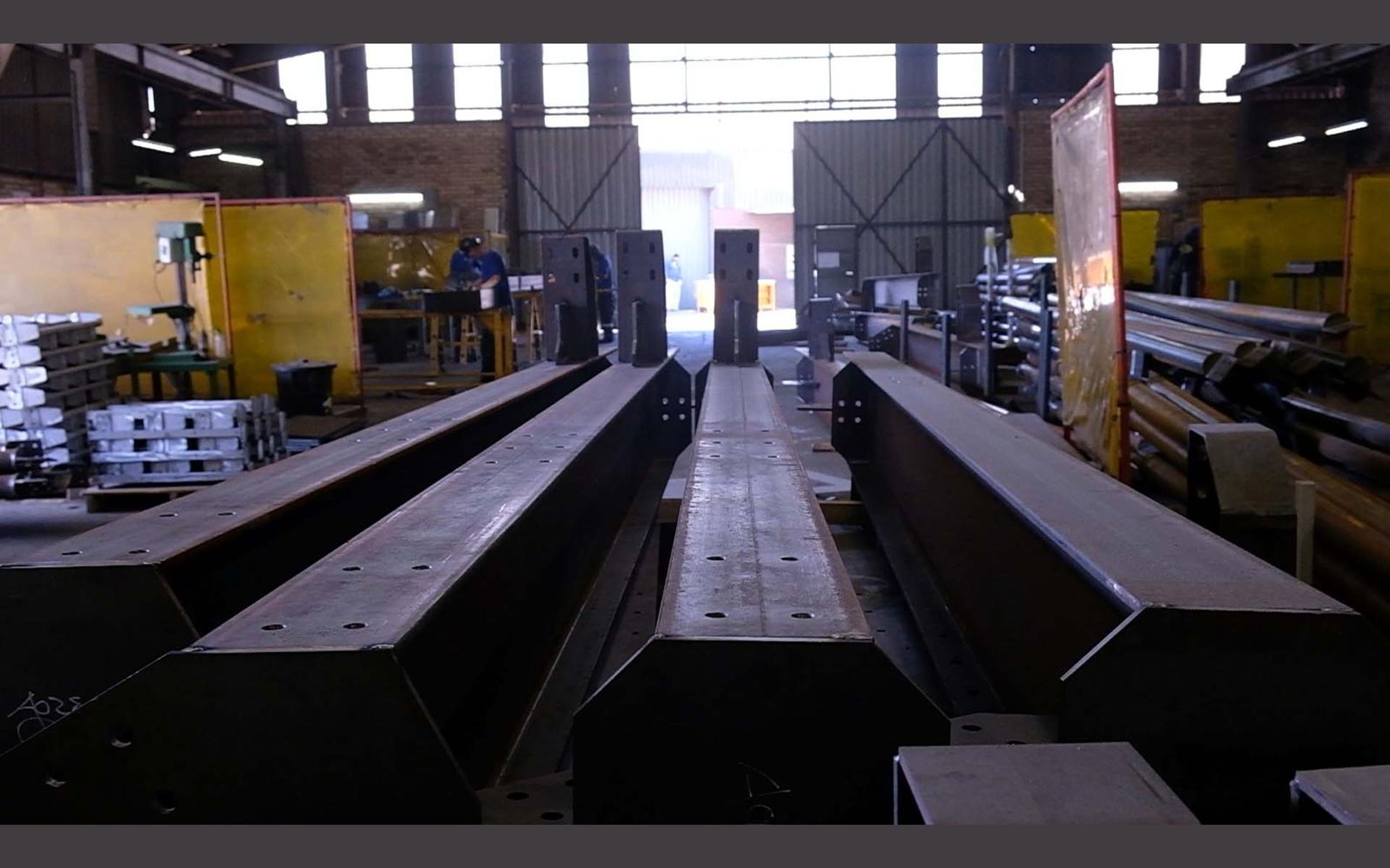 Fabrication bay with yellow welding screens and steel sections