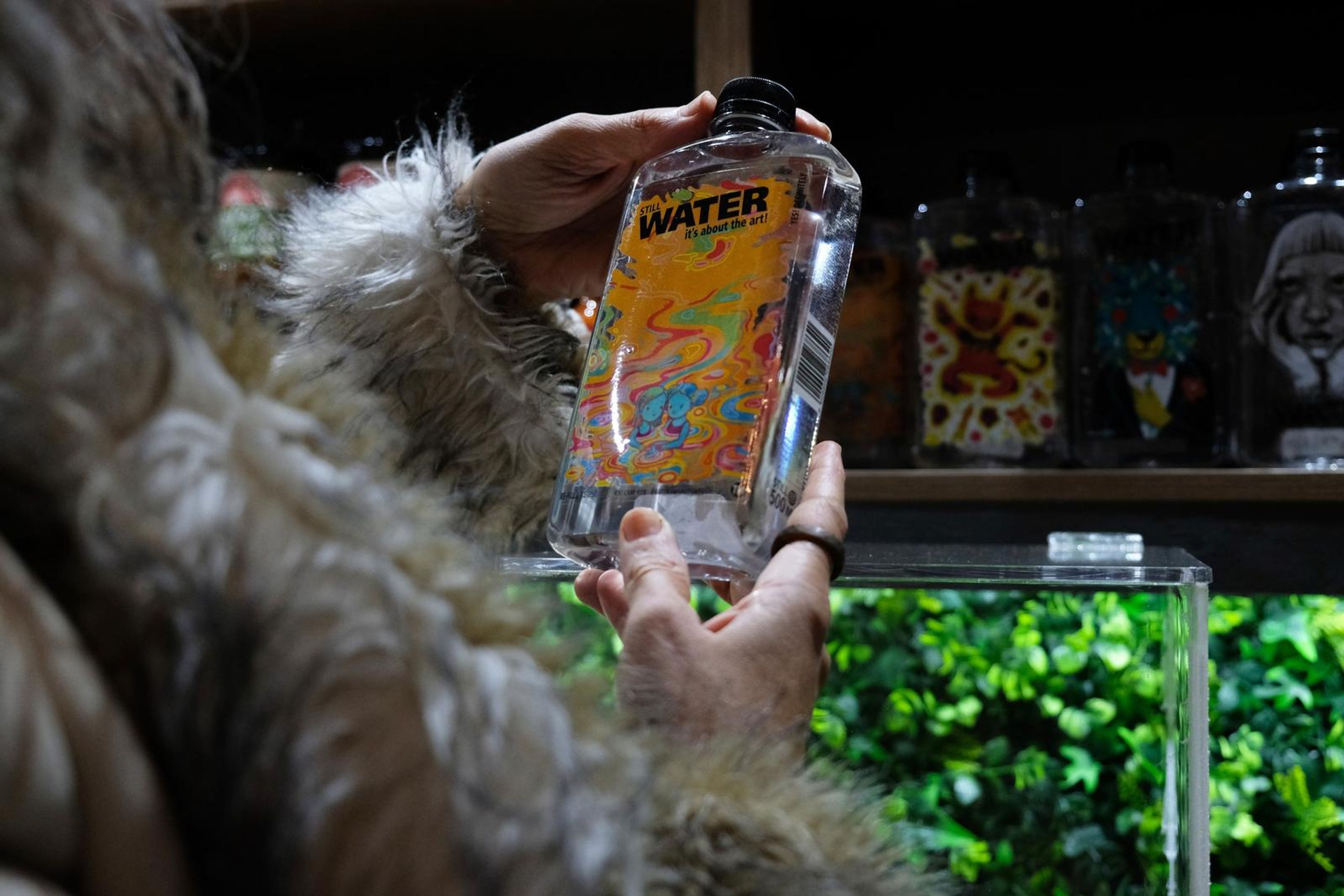 Hands holding an illustrated Water bottle from the shelf