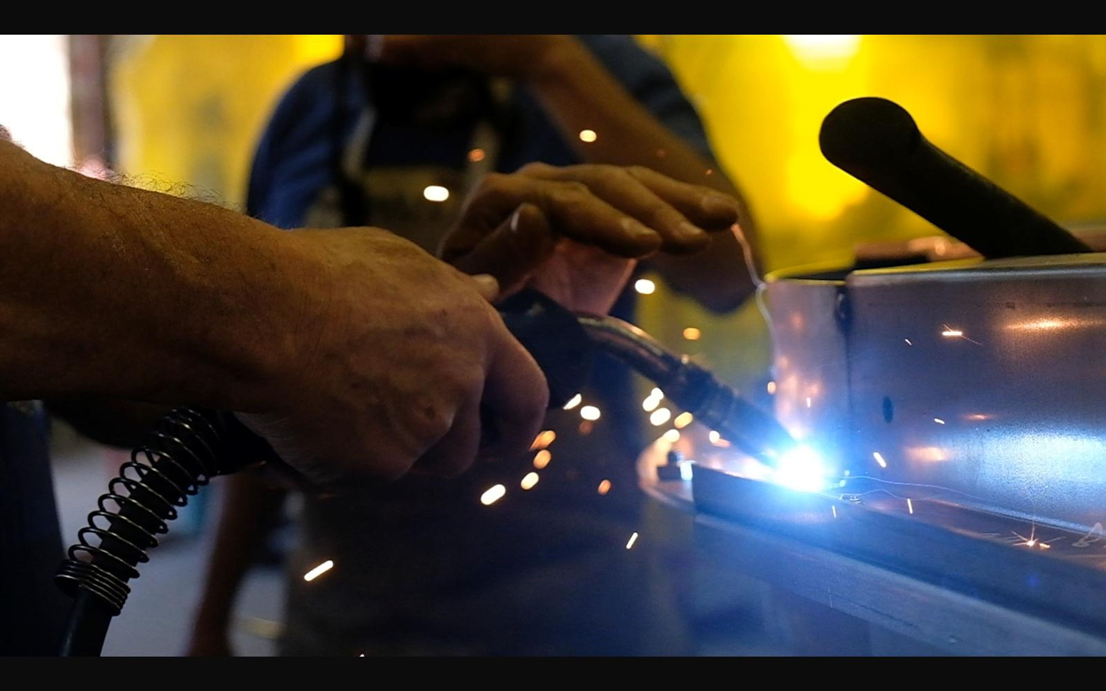 Hands welding with a MIG torch and sparks