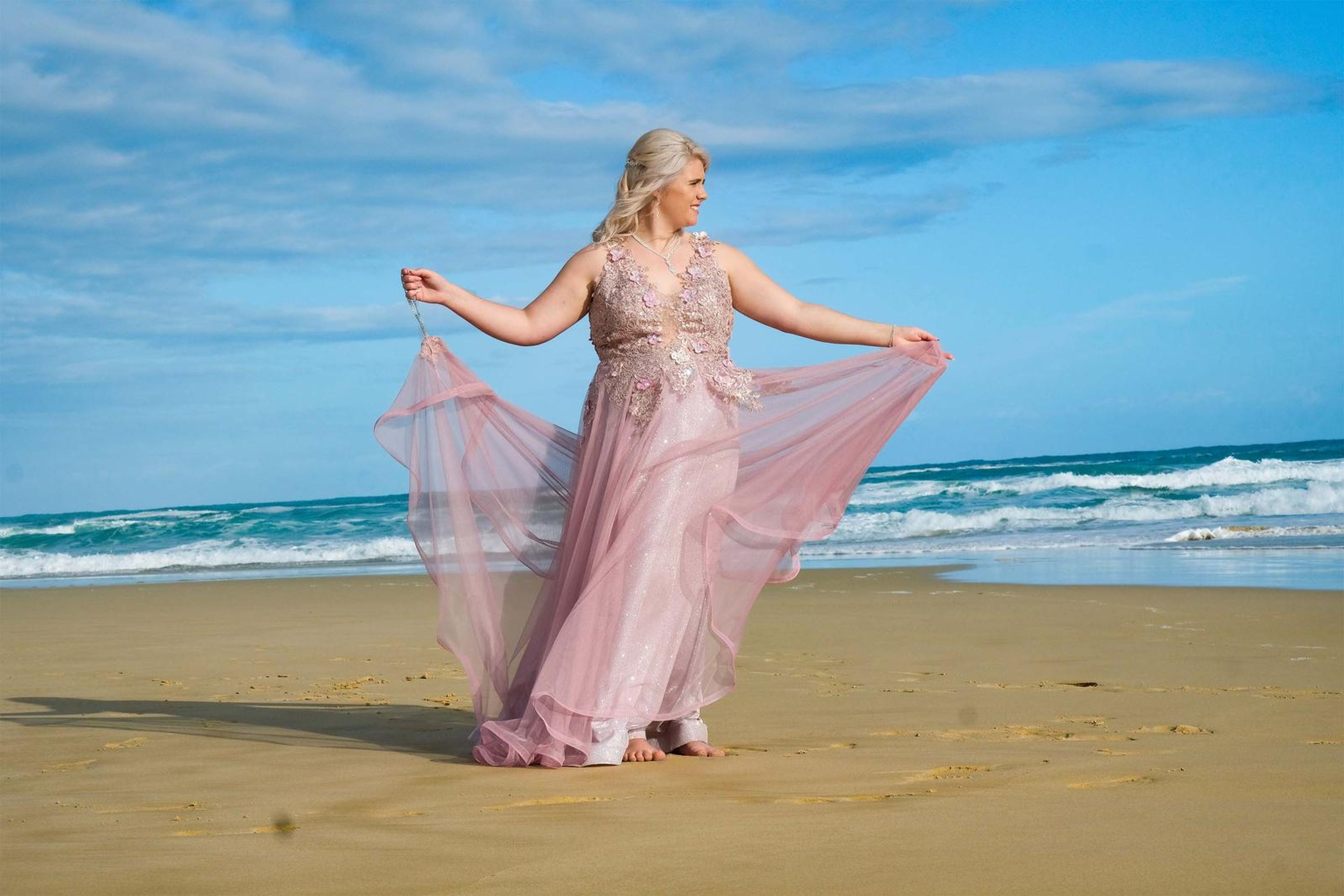 Holding out the gown beside the waves