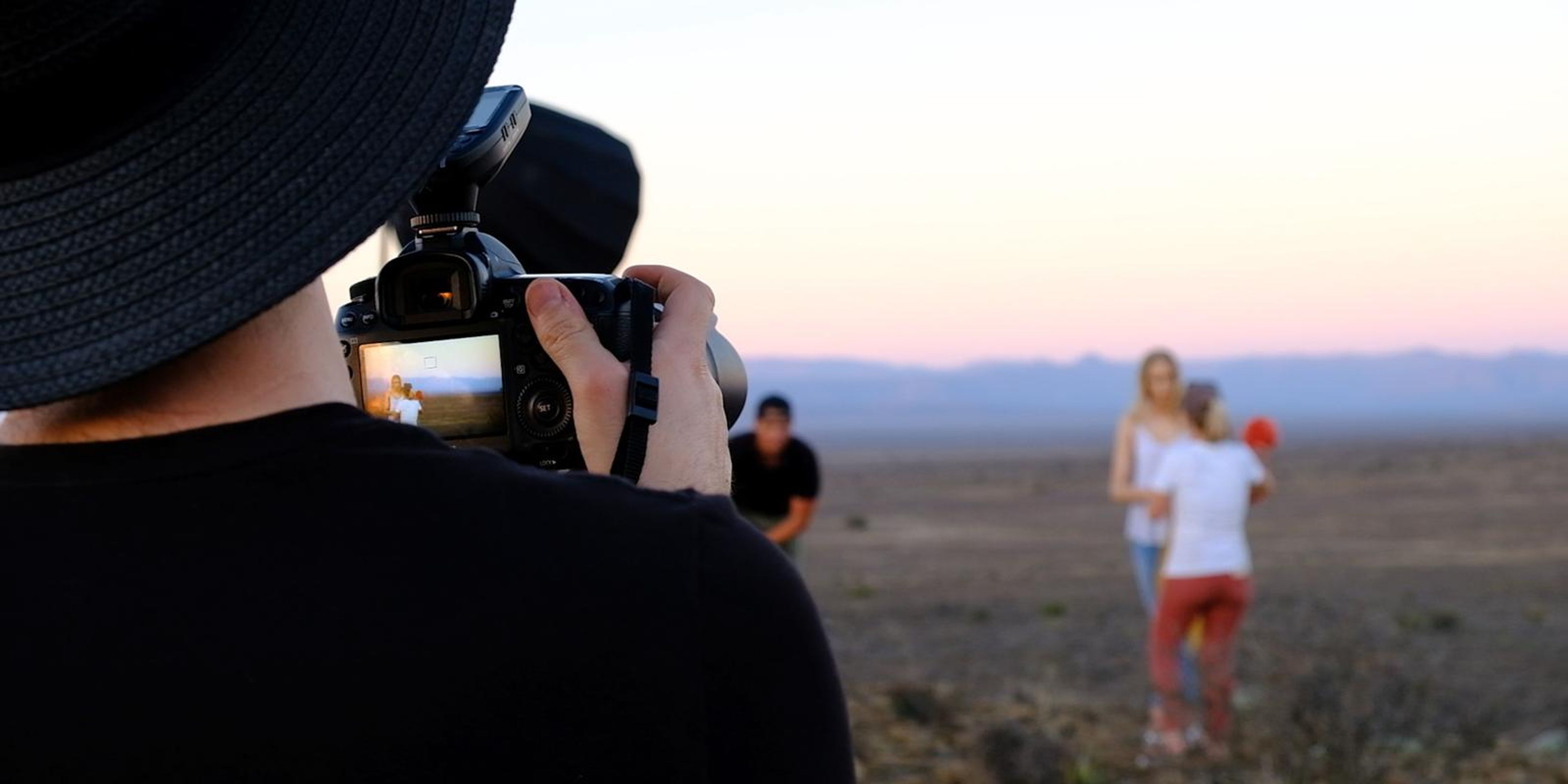 Photographer lining up a shot while the model and stylist wait in the distance