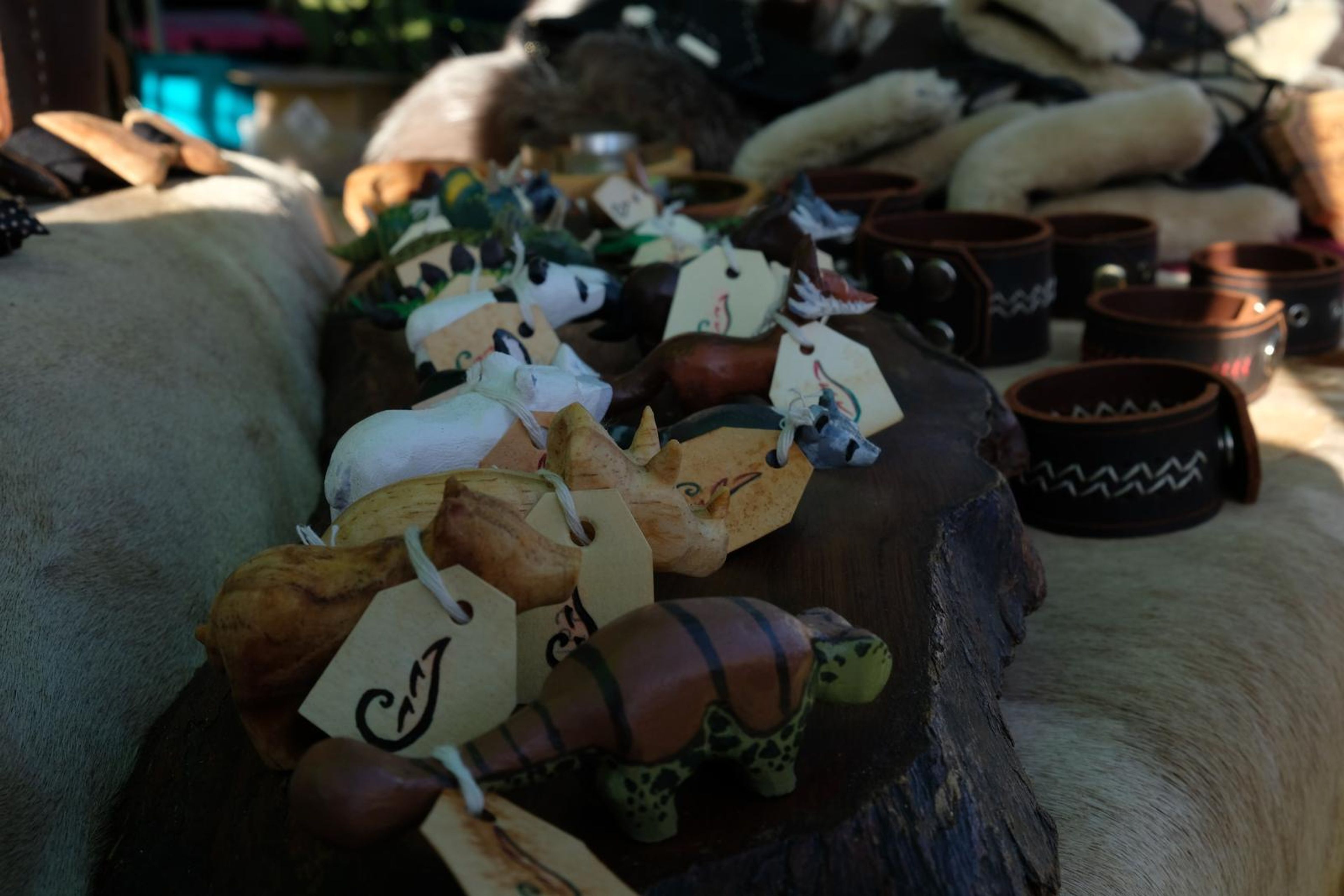 Hand-carved wooden animals with handwritten tags beside leather cuffs