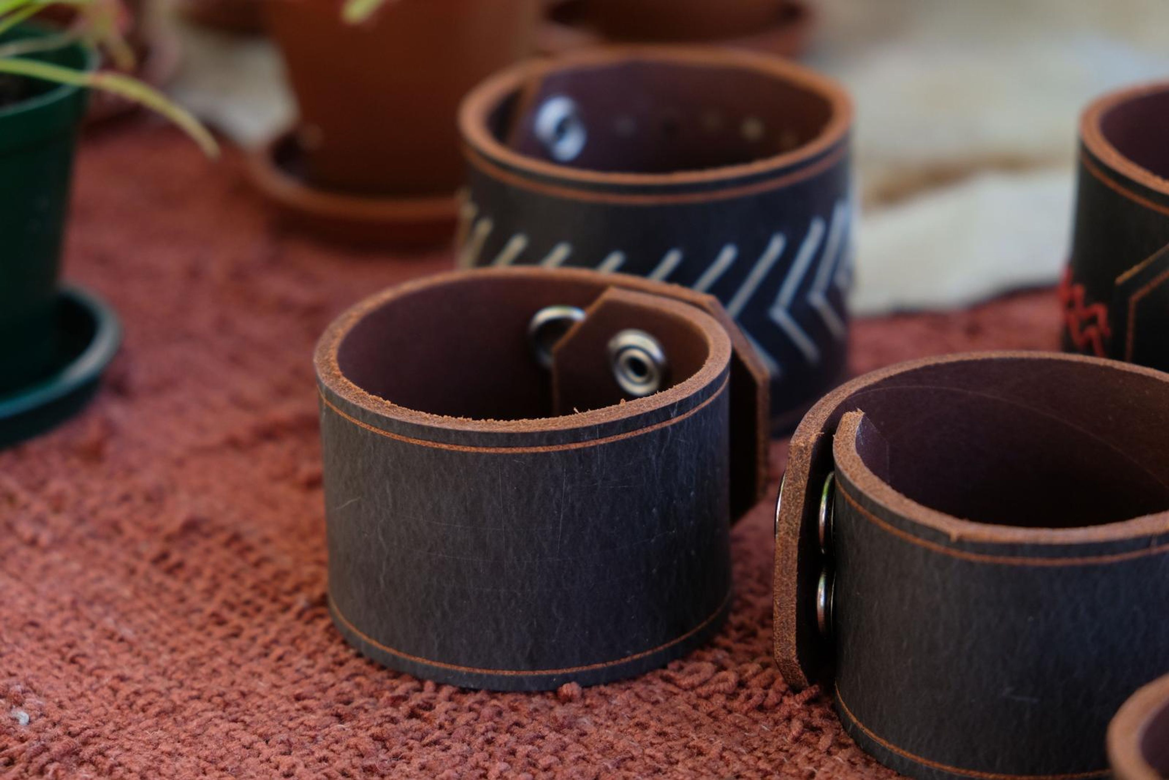 Dark leather cuffs with hand-stitched patterns on red cloth