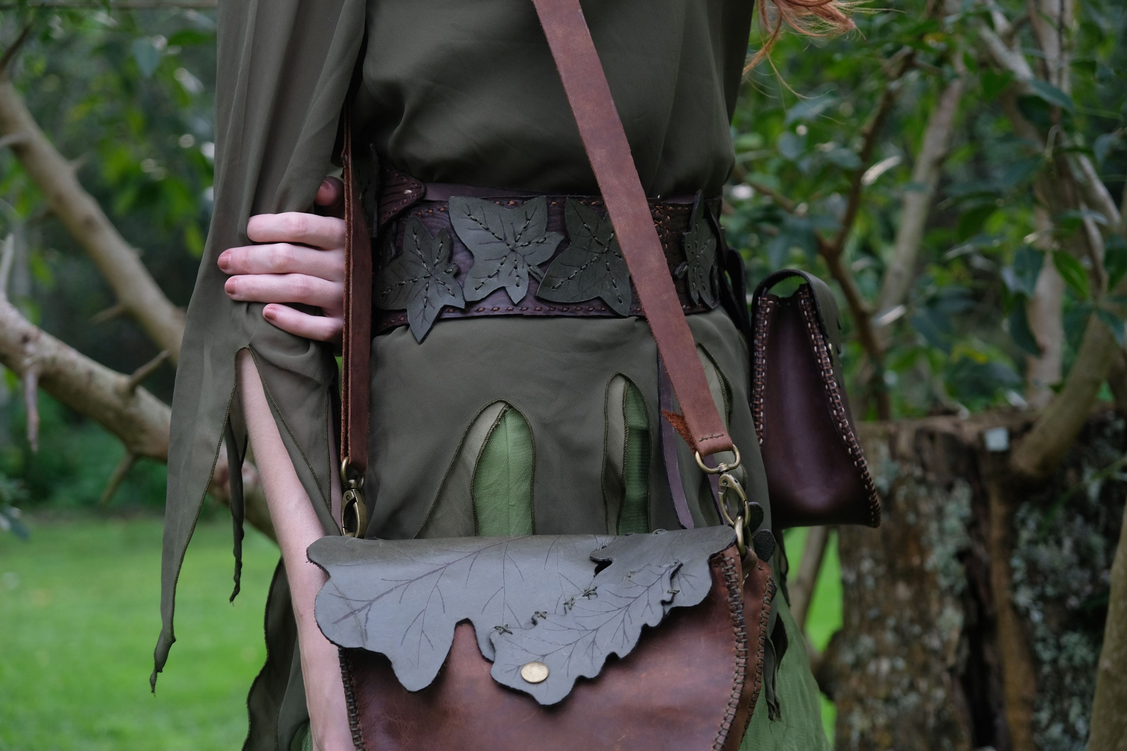 Leaf-shaped leather bag flap on a belt over a green dress