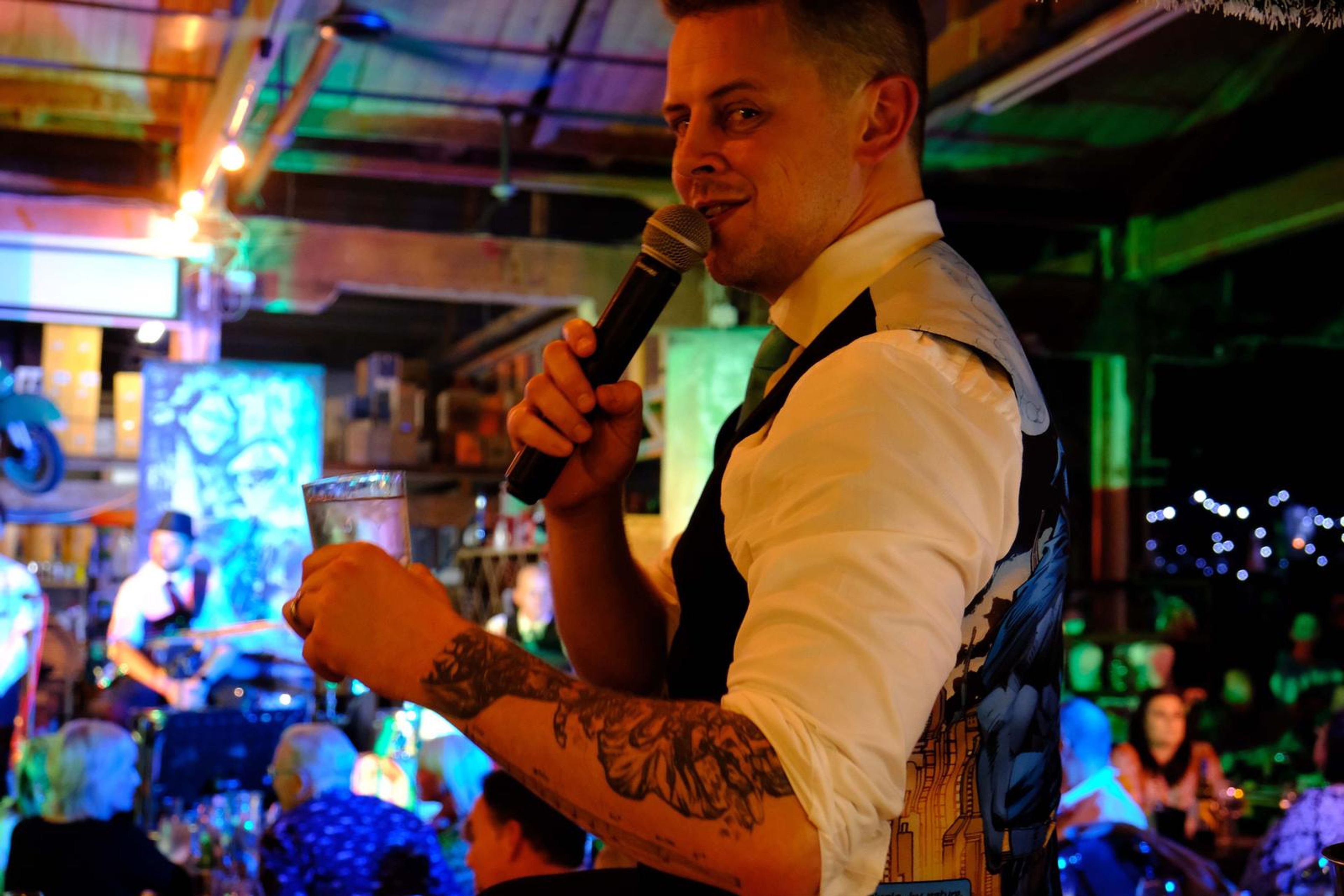 Singer in a waistcoat holding a glass and microphone