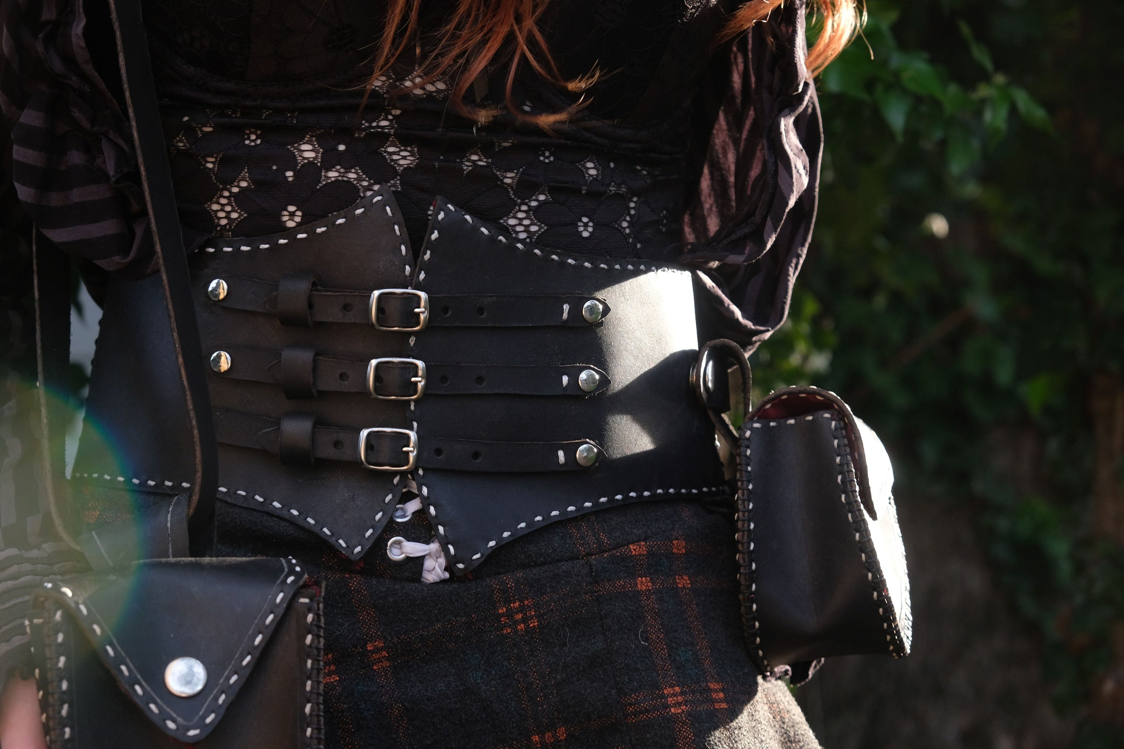 Close view of a black studded leather corset belt with buckles and a pouch