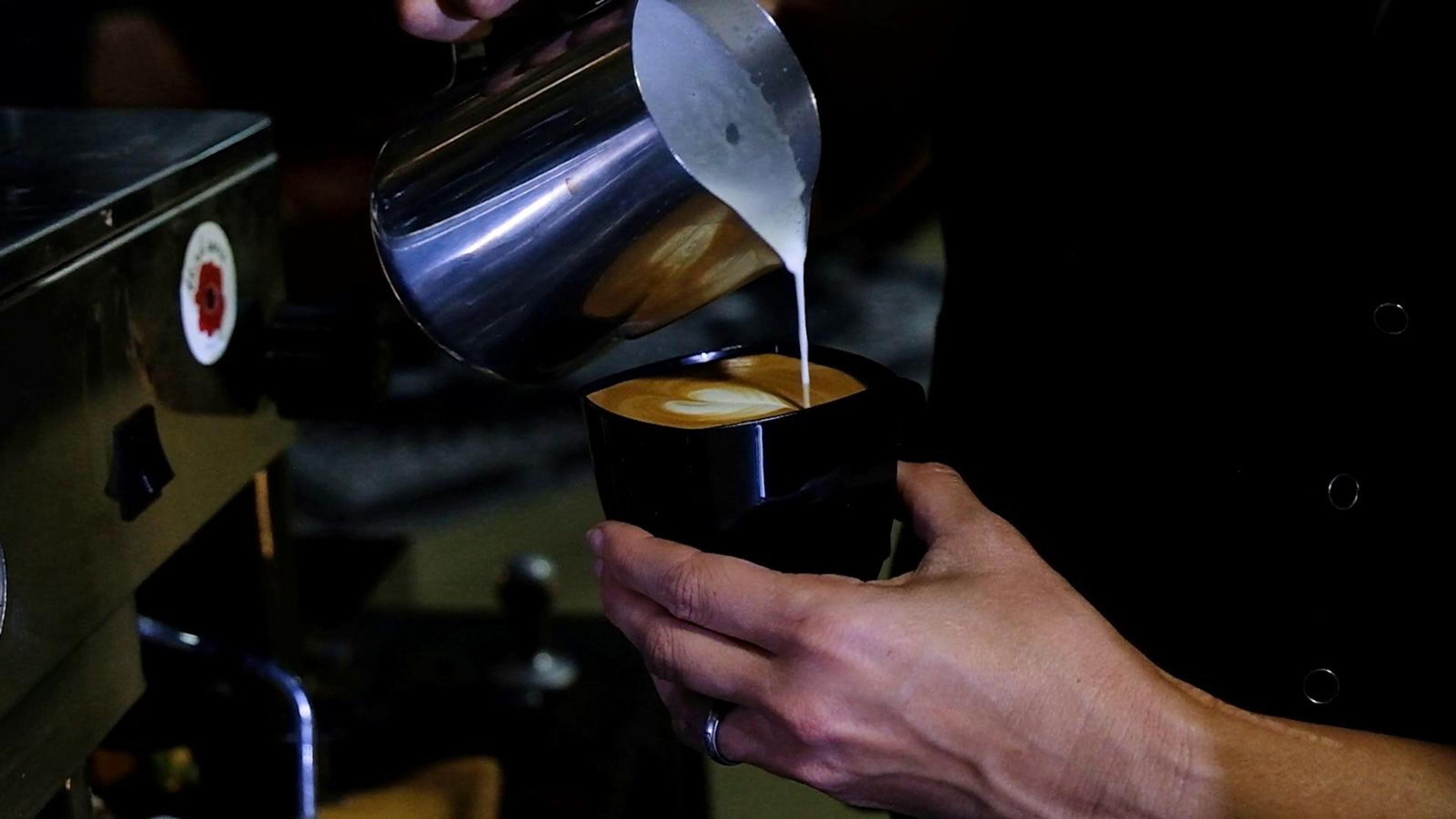 Barista finishing a latte at the coffee bar