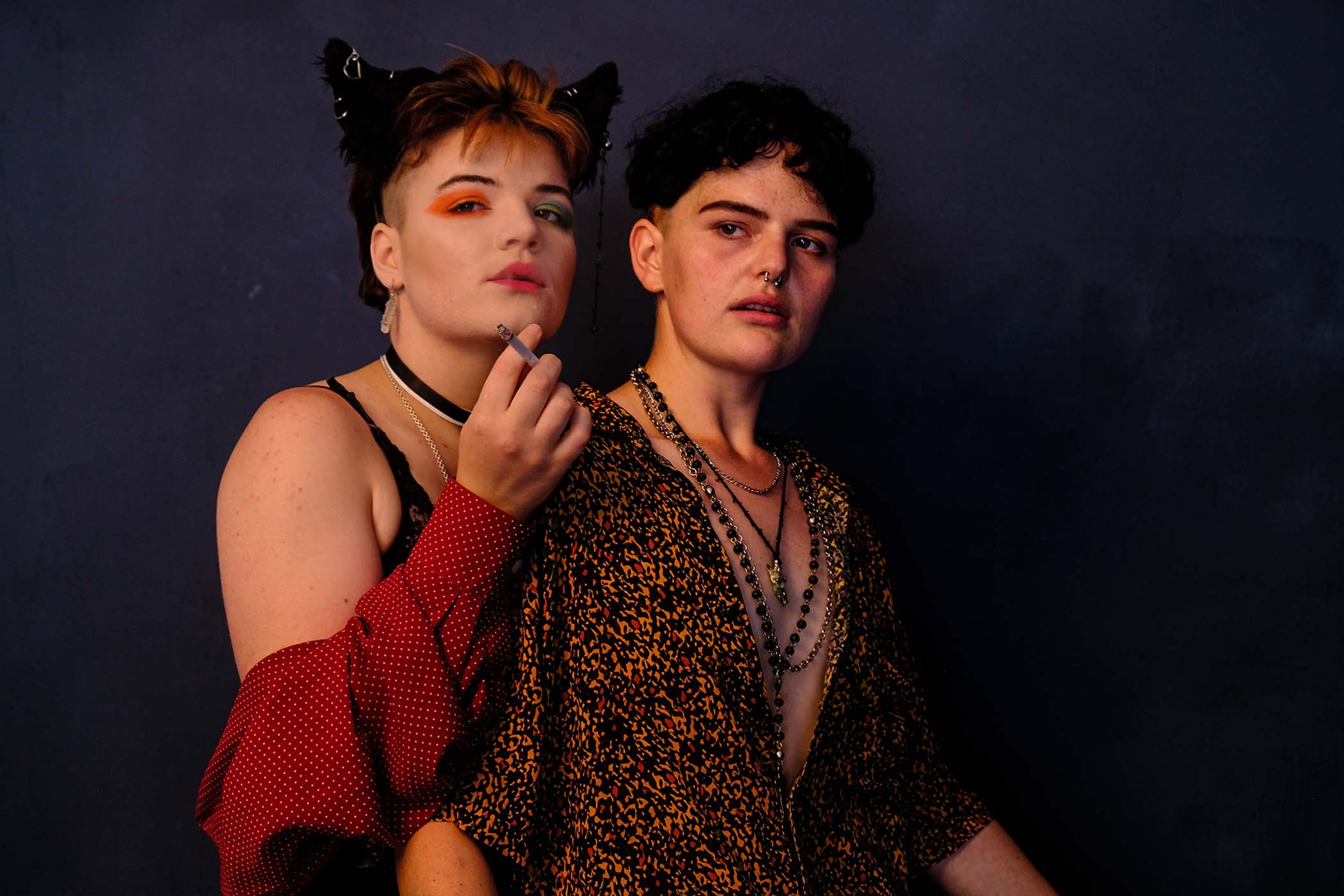 Portrait of a couple standing close together in patterned shirts and layered necklaces