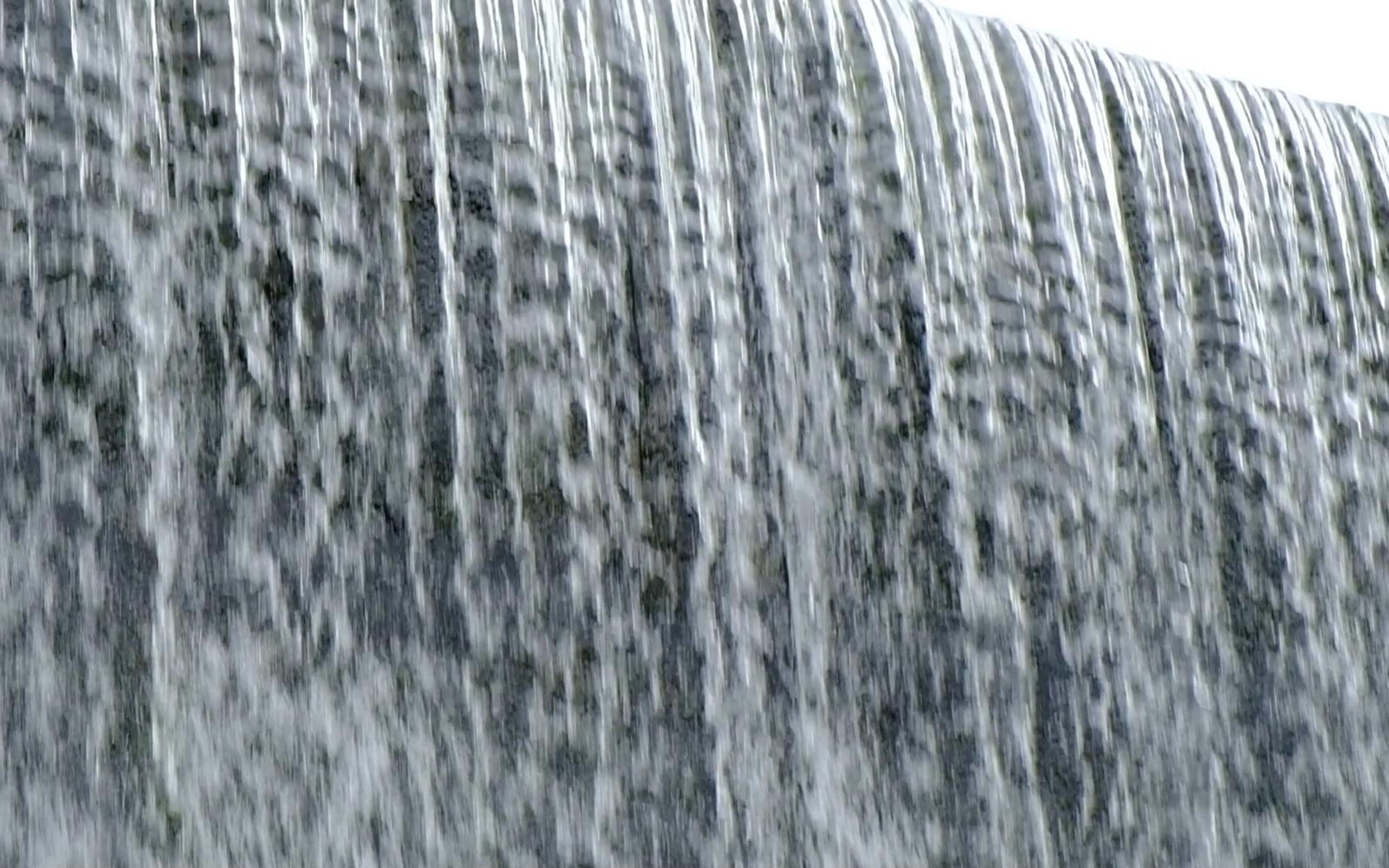 Tall sheets of falling water with textured streaks across the full frame
