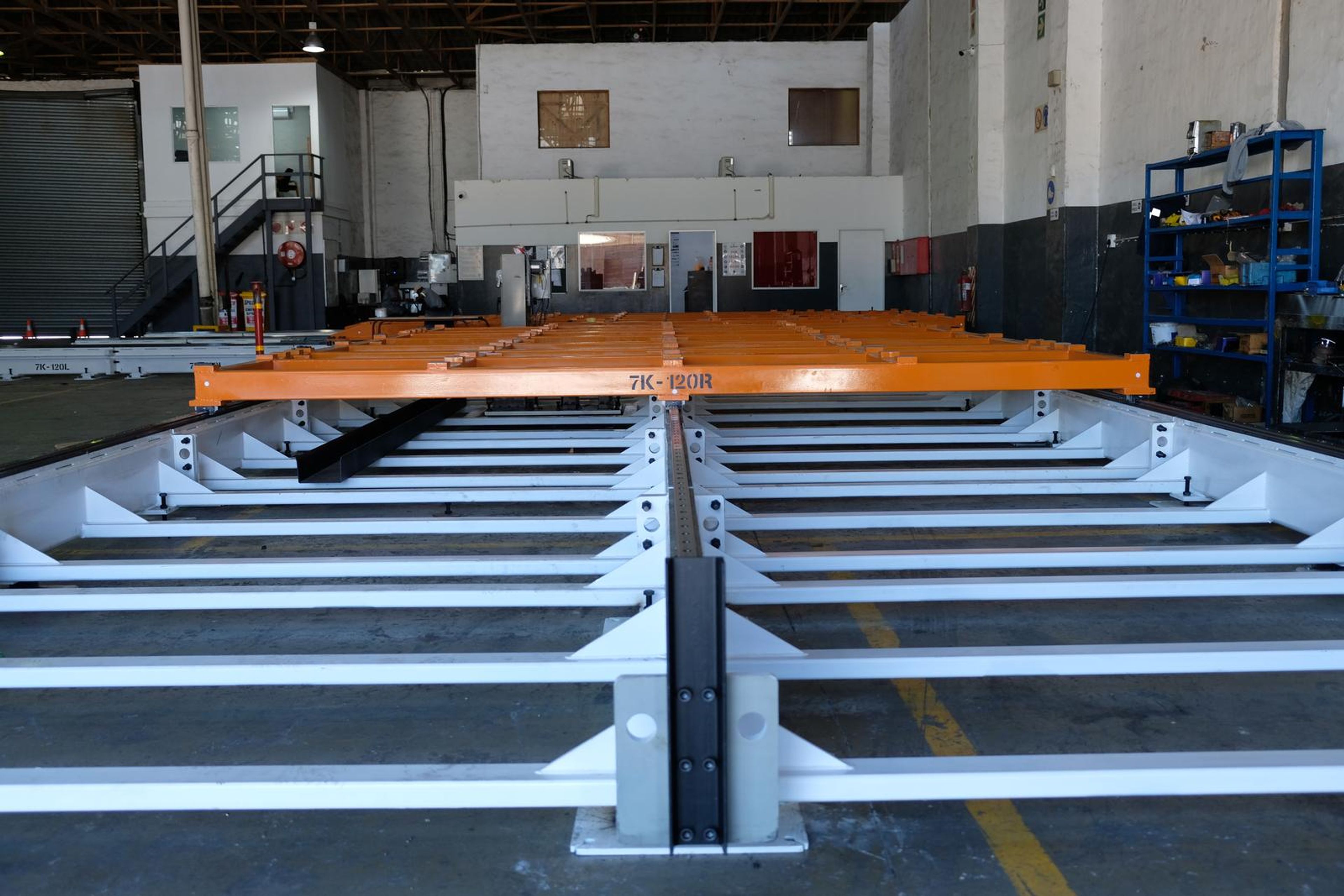 Orange cross beam on a white steel base seen along the central rail